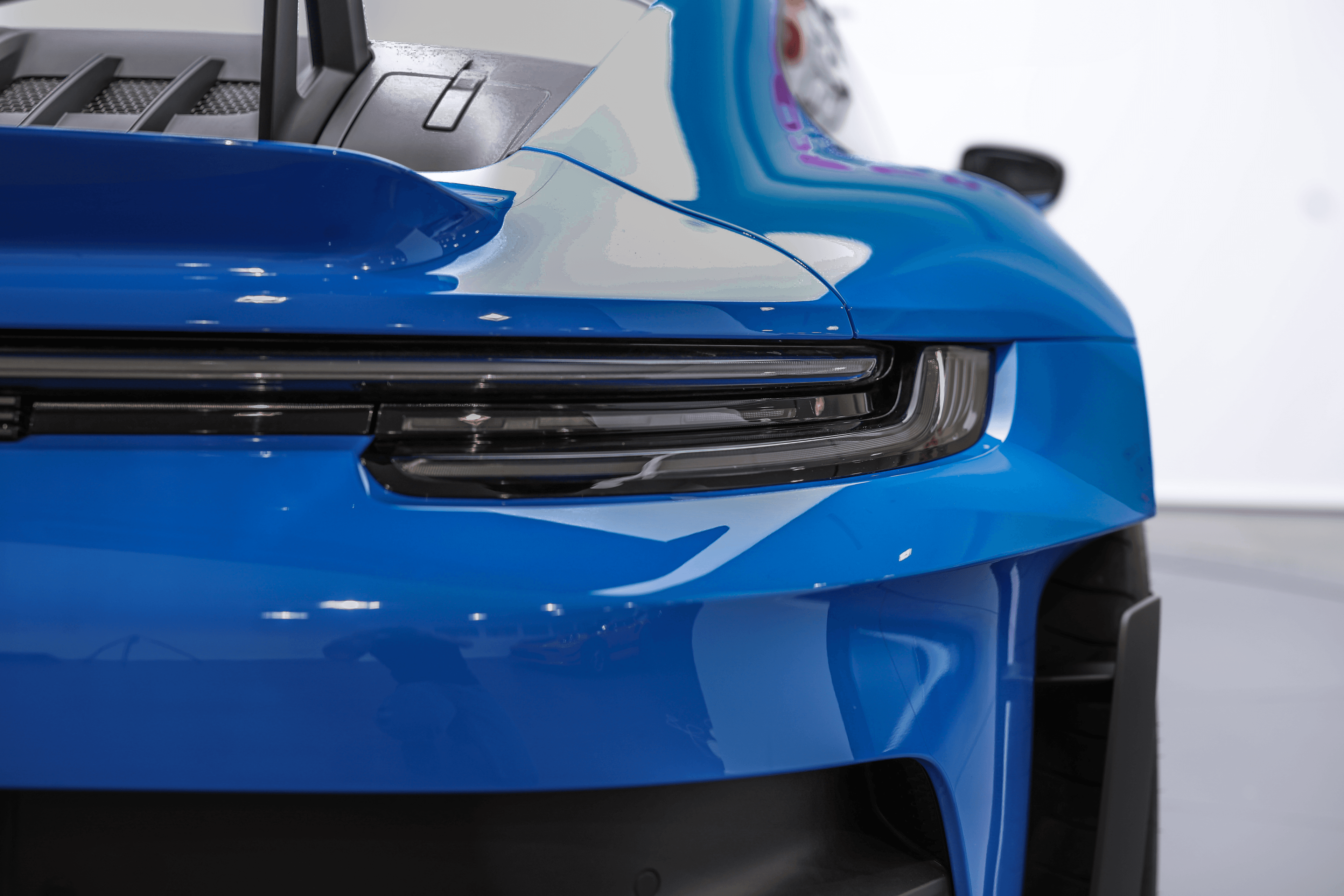 Focus sur le phare arrière de la Porsche GT3RS shark blue, mettant en avant son design moderne et aérodynamique, qui complète parfaitement l'esthétique sportive de la voiture.