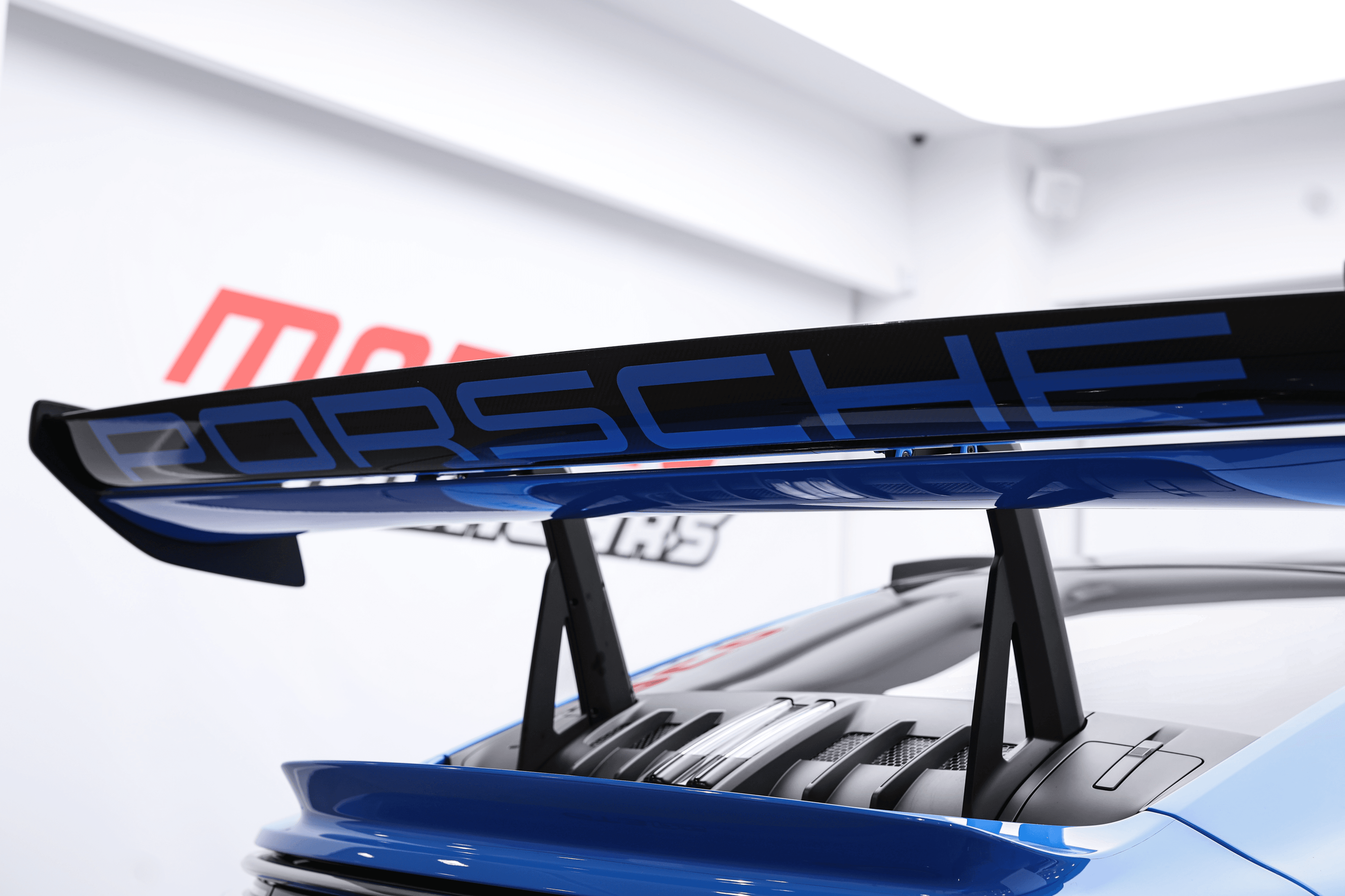 Zoom sur l'aileron arrière de la Porsche GT3RS bleue, mettant en avant son design aérodynamique et la finition soignée, essentiel pour maximiser l'appui à haute vitesse.
