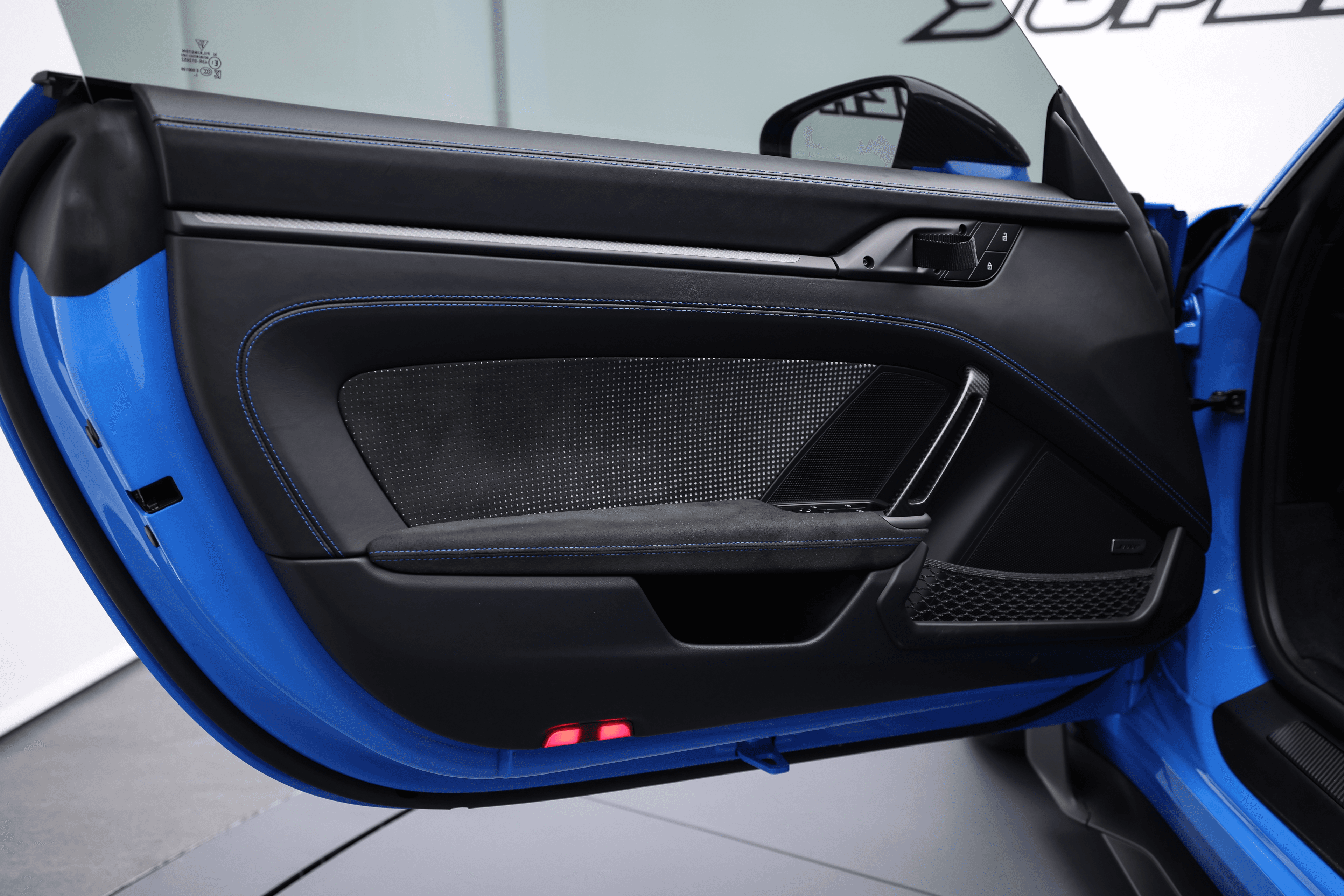 Intérieur de la porte de la Porsche GT3RS bleue, mettant en avant les matériaux haut de gamme et le design sportif, soulignant le mélange de confort et de performance.
