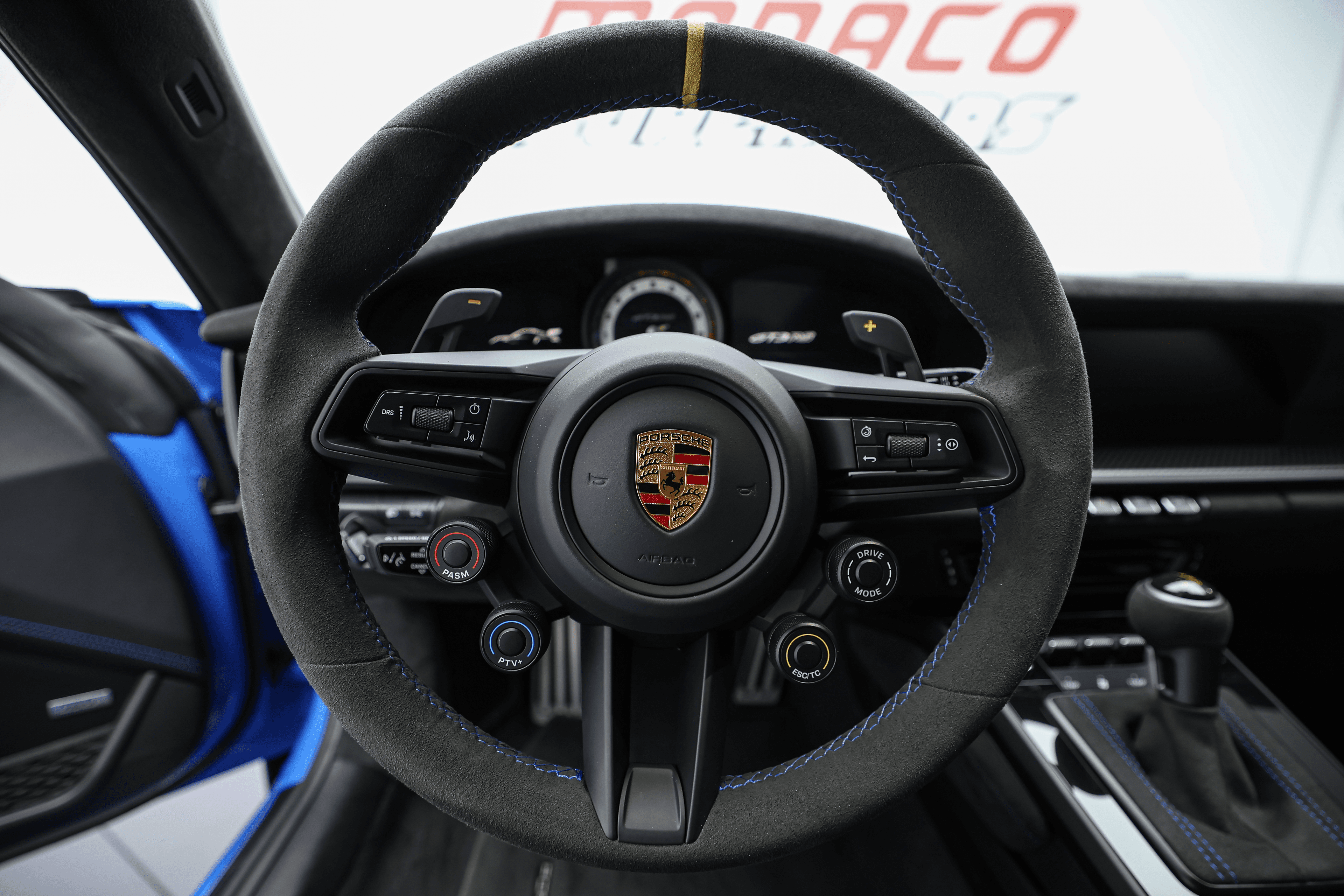 Vue du volant de la Porsche GT3RS bleue, avec ses finitions en Alcantara et ses commandes sportives, représentant le parfait équilibre entre ergonomie et performance.