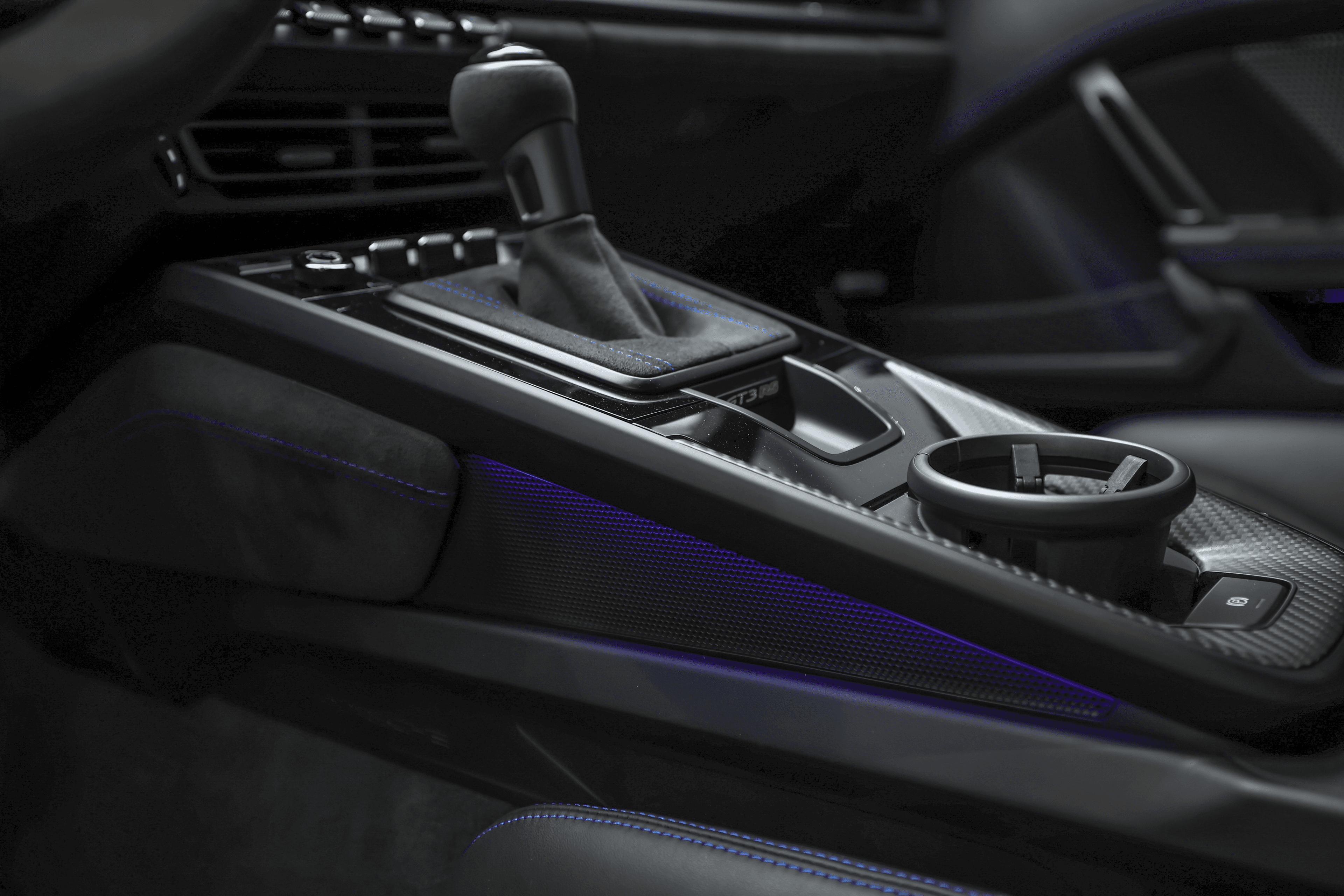 Détail de la console centrale de la Porsche GT3RS bleue, mettant en valeur le levier de vitesse et les éléments de design lumineux, combinant fonctionnalité et esthétique moderne.