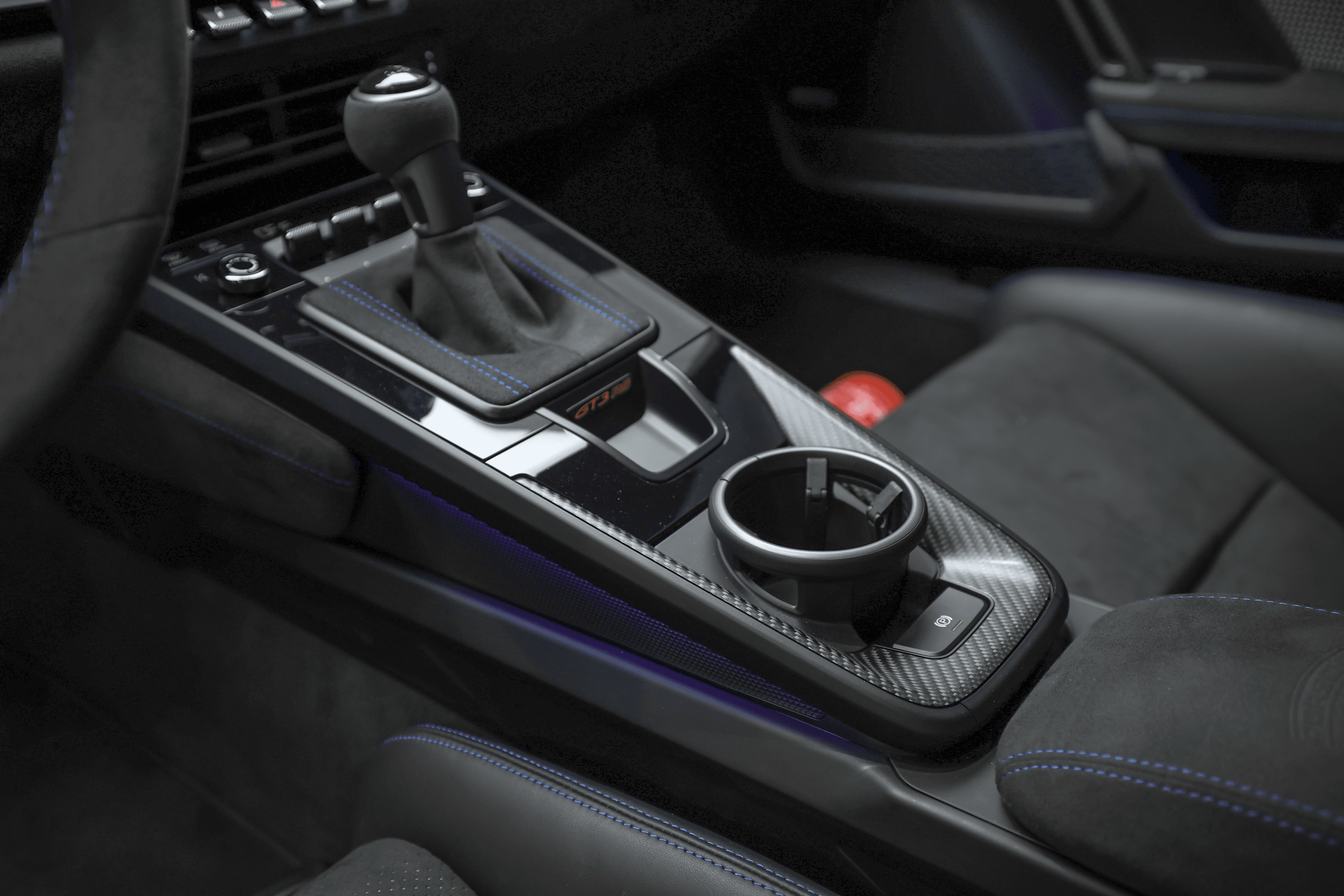 Détail de la console centrale de la Porsche GT3RS bleue, mettant en valeur le levier de vitesse et les éléments de design lumineux, combinant fonctionnalité et esthétique moderne.