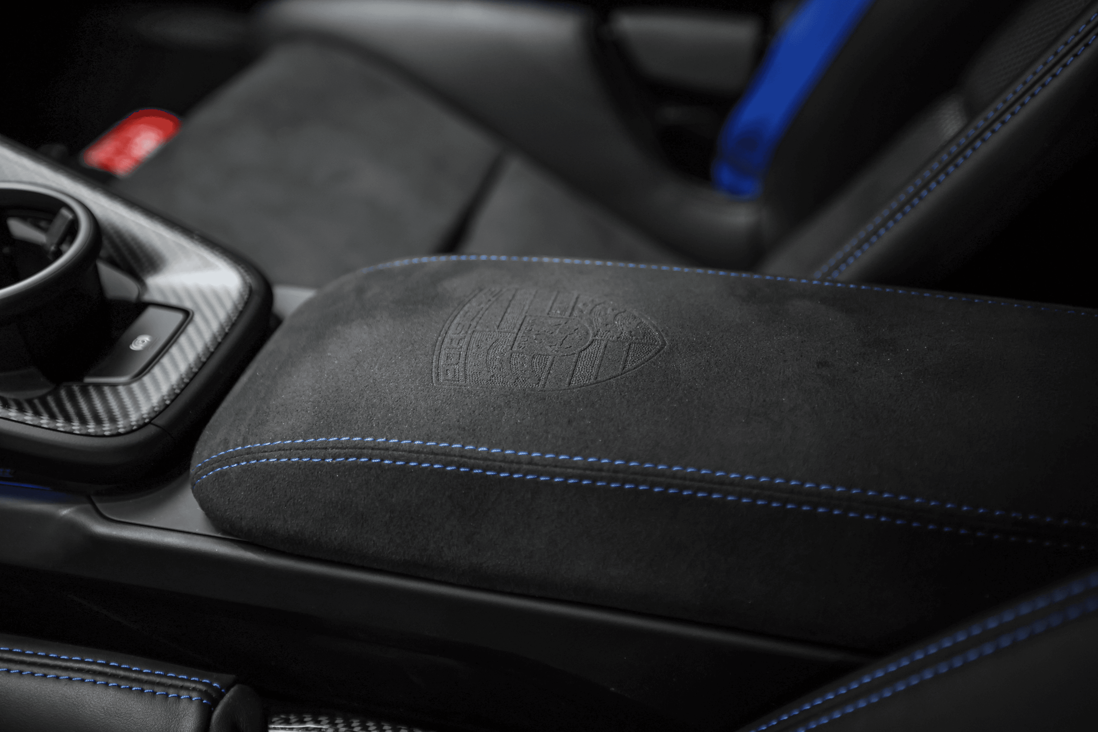 Détail de l'accoudoir de la Porsche GT3RS bleue, avec un logo discret gravé, mettant en avant les matériaux de luxe et l'attention portée aux détails.