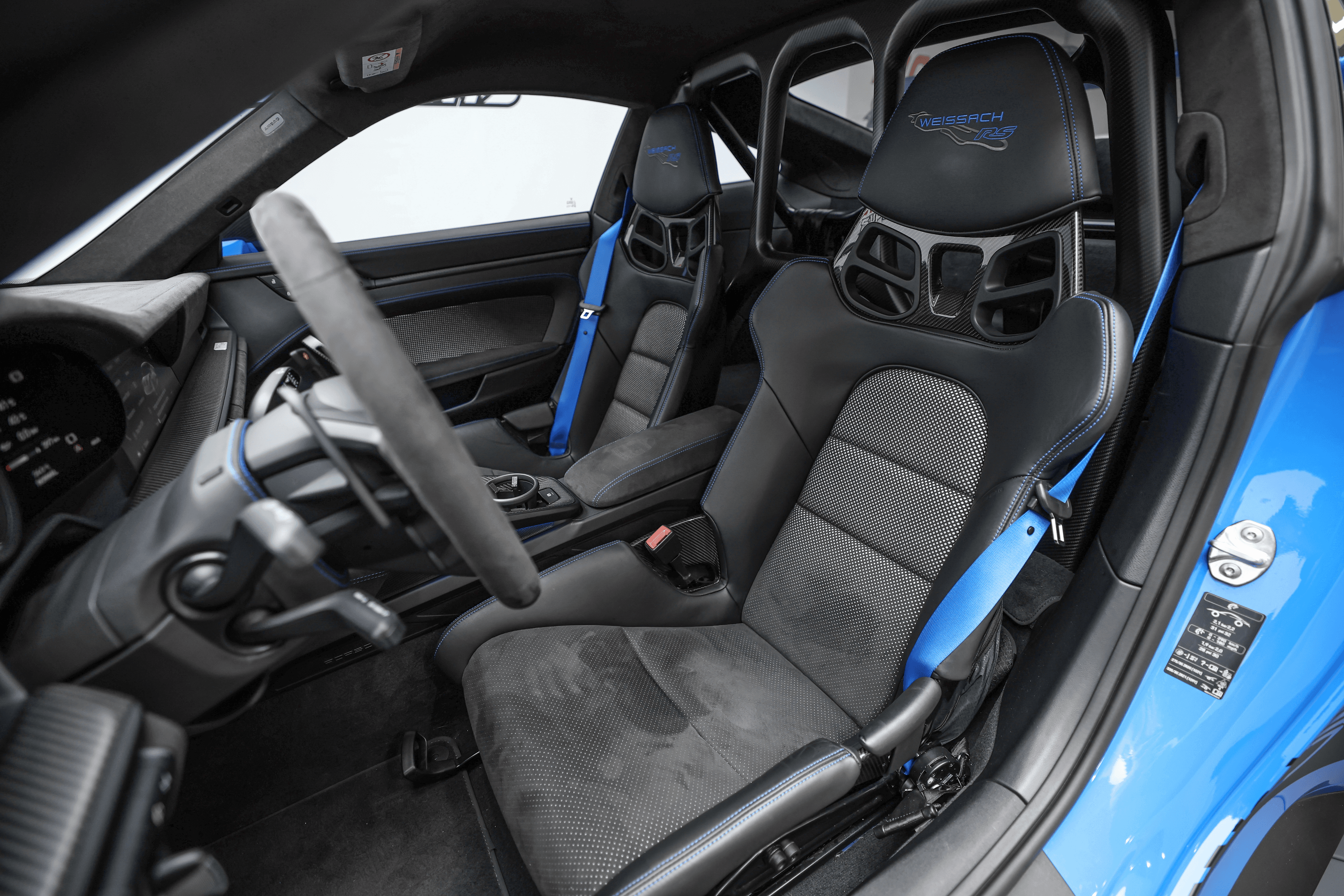 Vue intérieure de la Porsche GT3RS bleue, montrant le volant sport et les sièges baquets, conçus pour offrir un soutien optimal lors de la conduite dynamique.