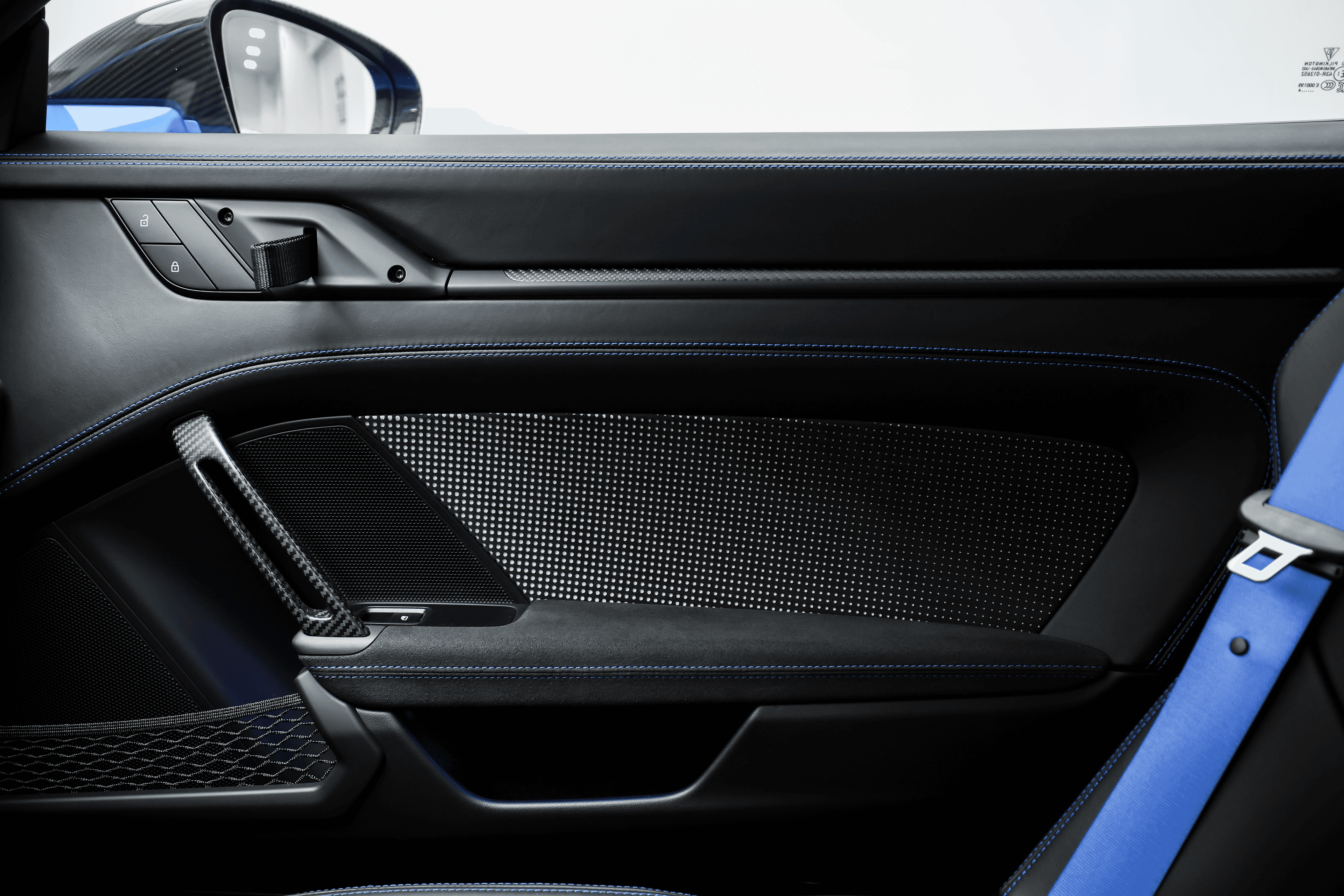 Détail de la porte de la Porsche GT3RS bleue, mettant en valeur les matériaux en carbone et le design épuré, soulignant le mélange de luxe et de sportivité.