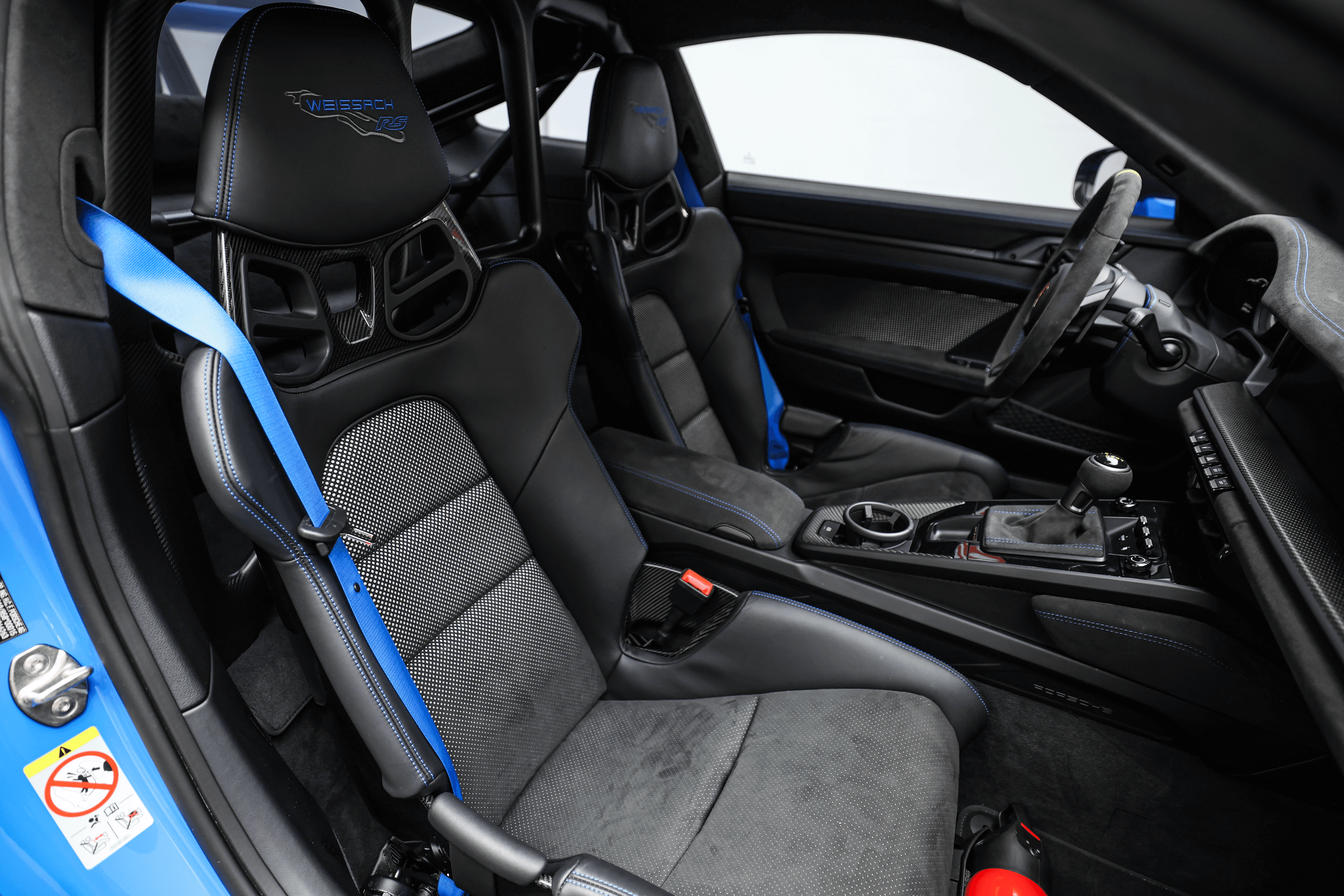 Vue intérieure de la Porsche GT3RS bleue, mettant en avant les sièges baquets et les détails de finition, illustrant l'engagement pour la performance et le confort.