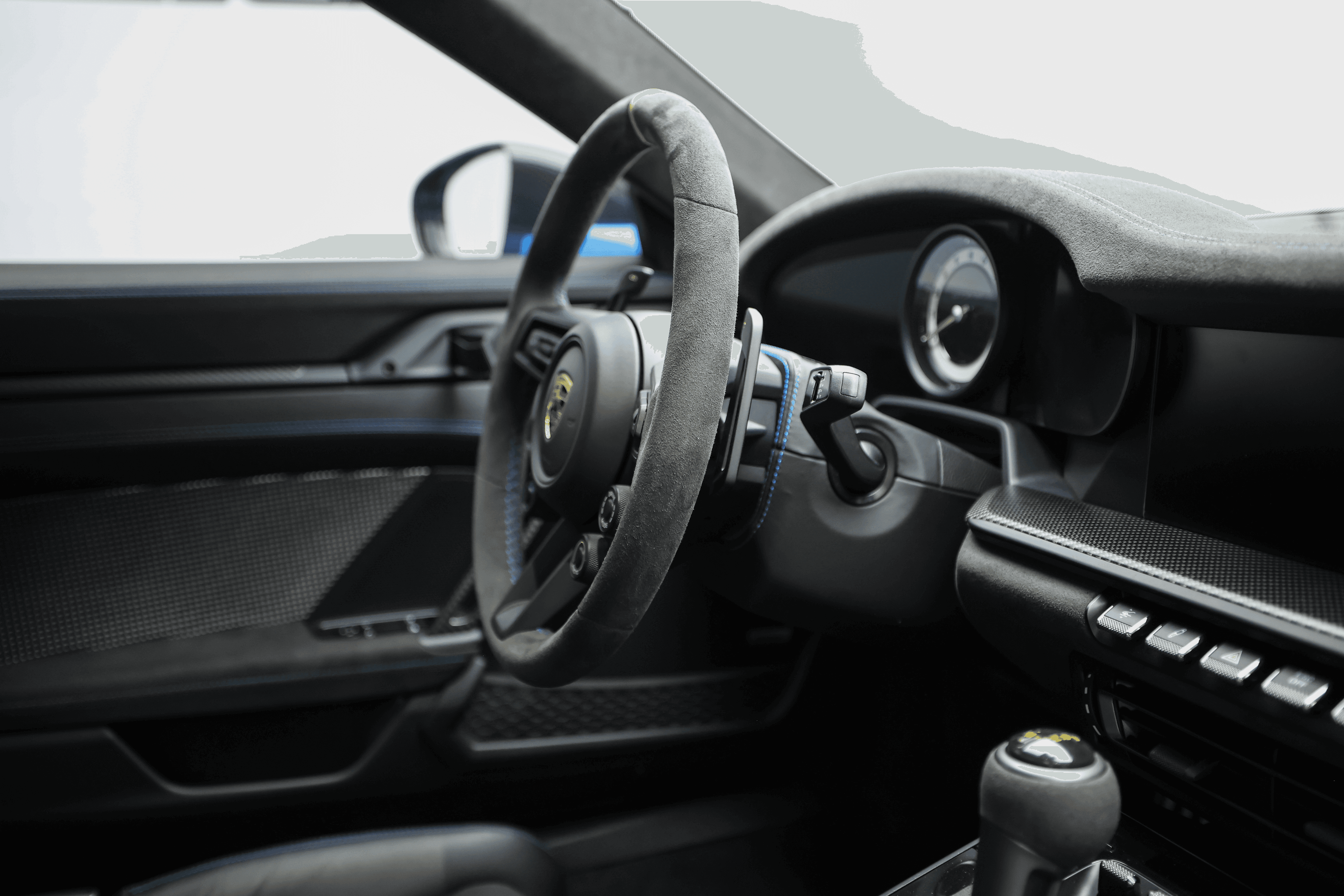 Vue du volant de la Porsche GT3RS, mettant en avant le design sportif et les matériaux haut de gamme, avec un tableau de bord minimaliste axé sur la performance.