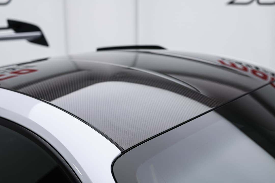 Cette vue de la Porsche 911 GT3 RS entièrement en carbone illustre l'engagement de la marque envers la légèreté et la performance, avec une finition en fibre de carbone qui accentue son allure agressive tout en optimisant l'aérodynamisme et la réactivité sur piste.