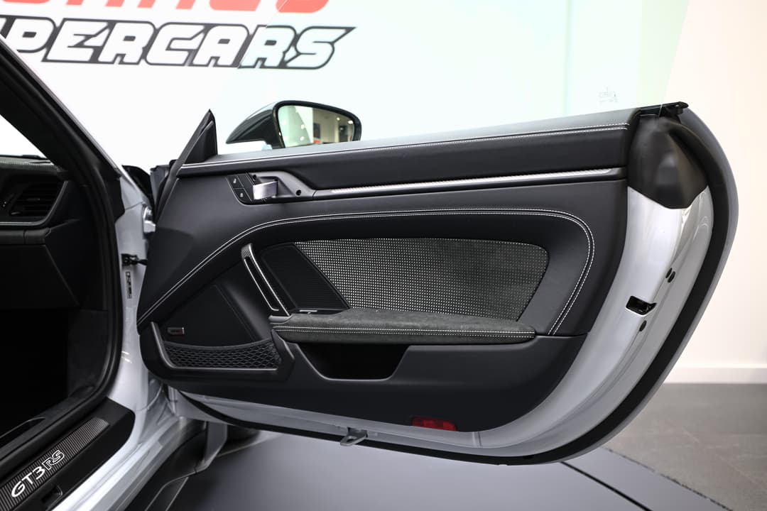 Cette vue de l'intérieur de la porte de la Porsche 911 GT3 RS montre un mélange raffiné de matériaux de qualité, avec des accents en carbone et des finitions soignées, offrant à la fois confort et fonctionnalité tout en restant fidèle à l'esthétique sportive de la voiture.