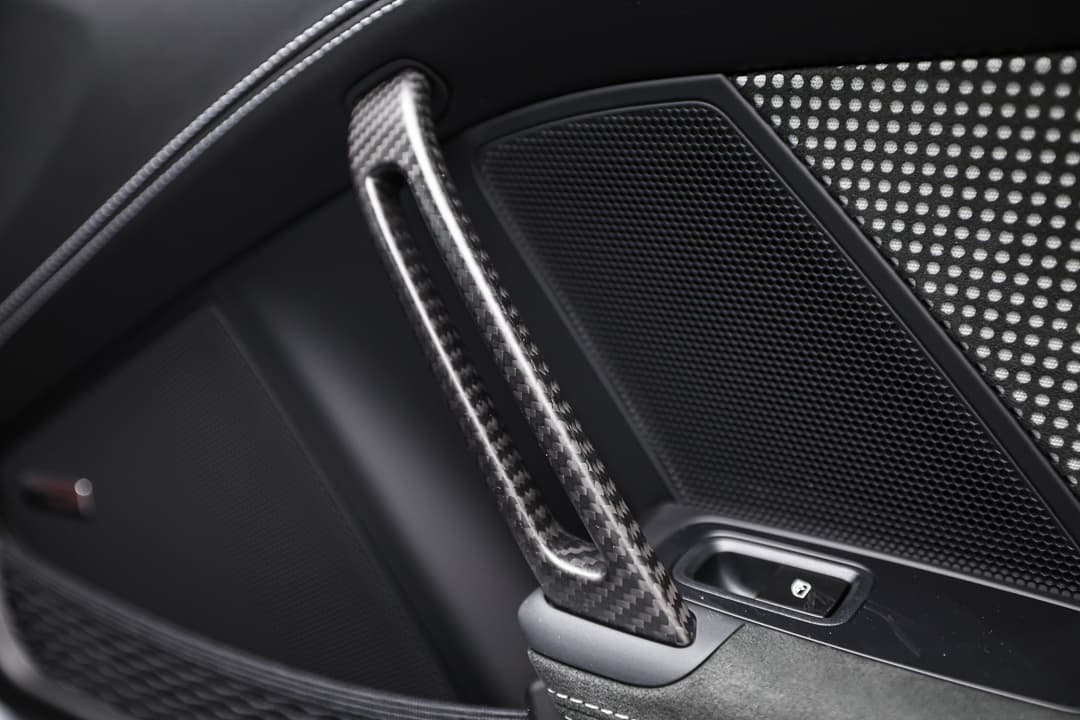 Cette vue du poignet en carbone à l'intérieur de la Porsche 911 GT3 RS souligne l'engagement de la marque envers la performance et l'innovation, offrant une finition légère et robuste qui rehausse l'esthétique sportive tout en assurant une prise en main optimale des commandes.
