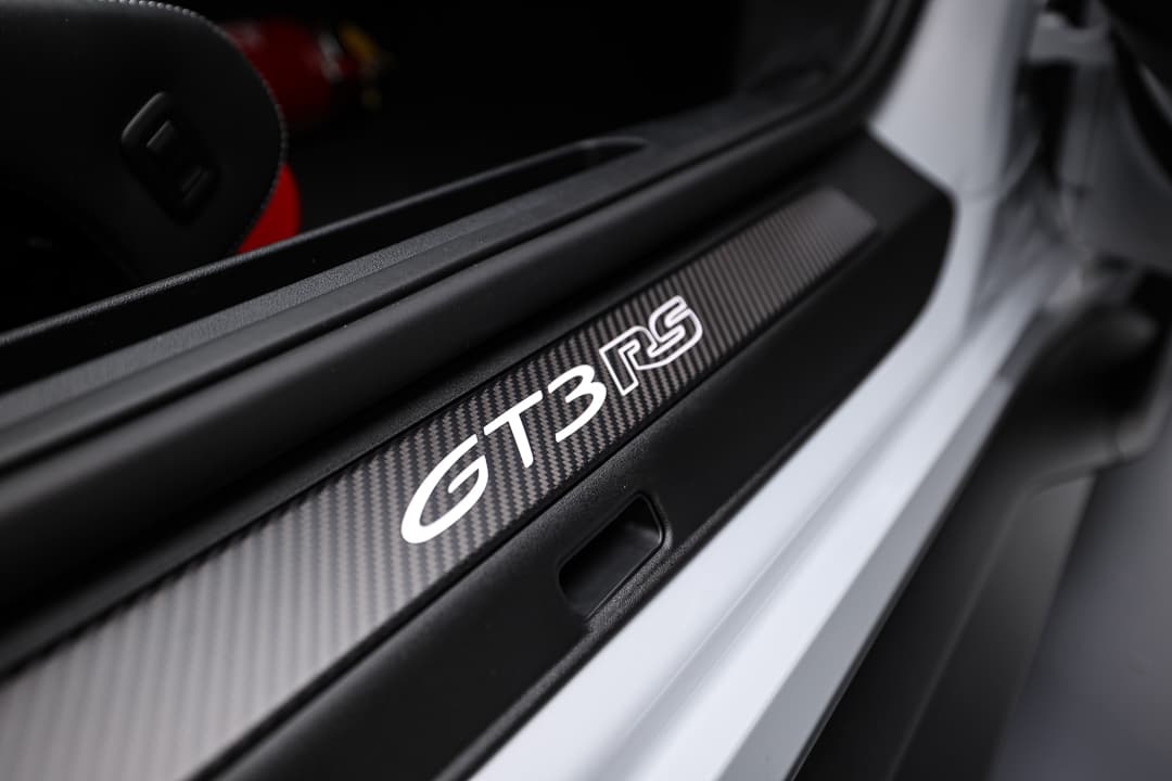 Cette image du seuil de porte de la Porsche 911 GT3 RS met en valeur un design distinctif et robuste, avec des éléments en carbone et des inscriptions emblématiques, contribuant à l'esthétique sportive tout en facilitant l'accès à l'habitacle.