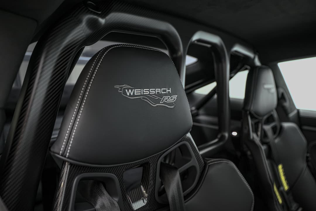 Cette vue de l'arceau en carbone et du siège du pack Weissach de la Porsche 911 GT3 RS illustre l'engagement de la marque envers la légèreté et la performance, offrant une structure renforcée tout en réduisant le poids, pour une expérience de conduite encore plus agile sur circuit.