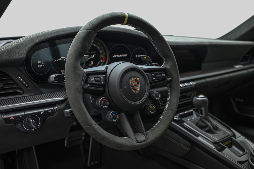 Voici une phrase pour décrire une photo du tableau de bord de loin de la Porsche 911 GT3 RS :  "Cette vue éloignée du tableau de bord de la Porsche 911 GT3 RS offre une perspective globale sur le cockpit, mettant en avant l'harmonie entre les éléments de design, la disposition des instruments et l'ambiance sportive, tout en soulignant l'ergonomie dédiée à l'expérience de conduite."
