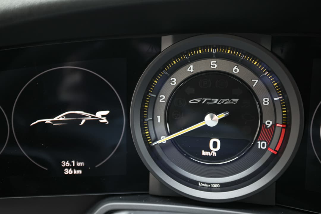 Cette vue du tableau de bord de la Porsche 911 GT3 RS met en avant un design sophistiqué et orienté vers le conducteur, avec des compteurs analogiques et numériques, des matériaux haut de gamme, et une interface technologique, créant un environnement à la fois performant et luxueux.