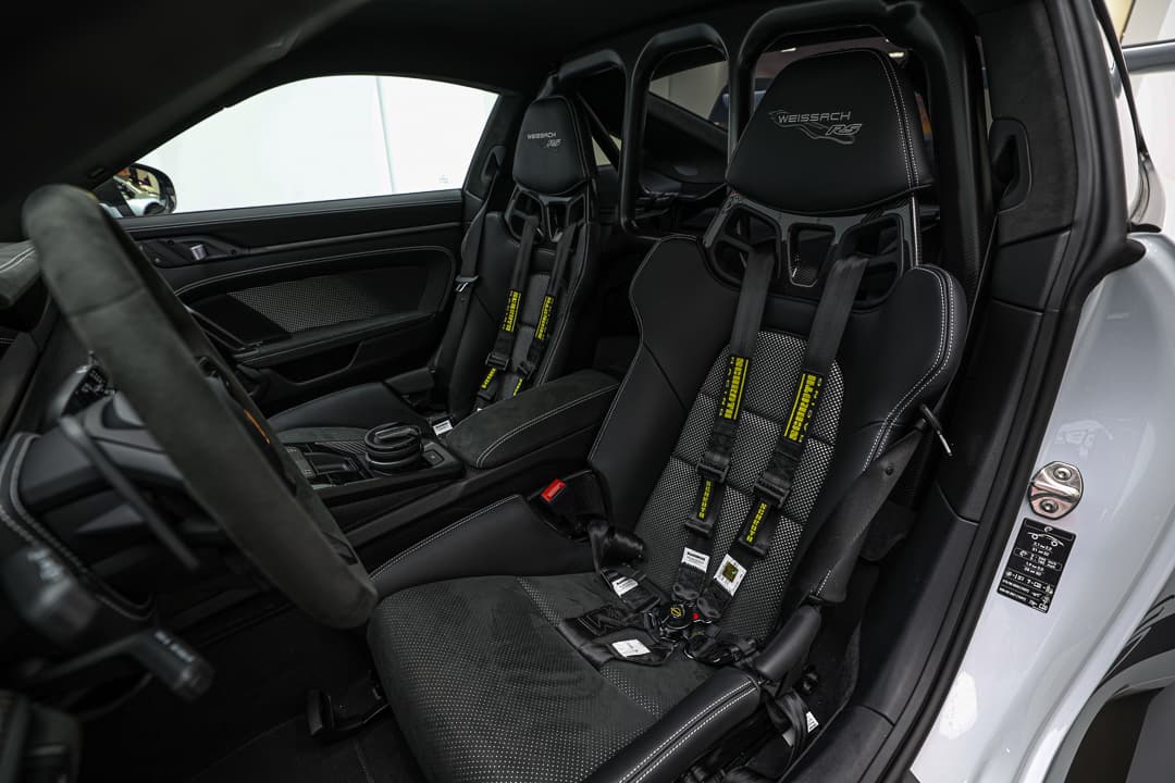 L'image présente les sièges baquets de la Porsche, visibles depuis le côté conducteur, mettant en avant leur design ergonomique, leur soutien latéral et les matériaux de haute qualité.