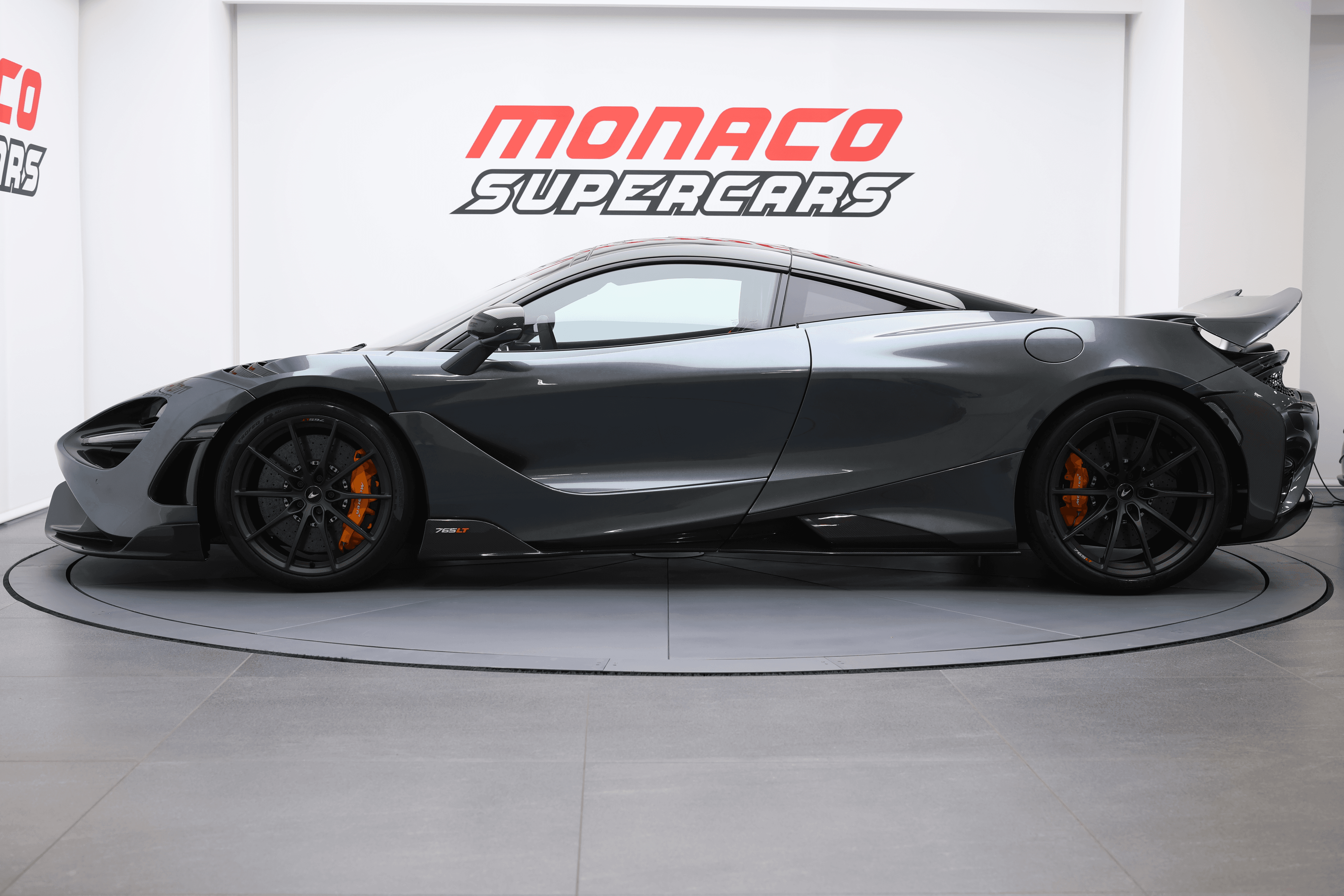 L'image capture le profil d'une McLaren 765LT, mettant en évidence ses lignes aérodynamiques, sa silhouette basse et ses détails agressifs, soulignant son design emblématique et sa performance exceptionnelle.