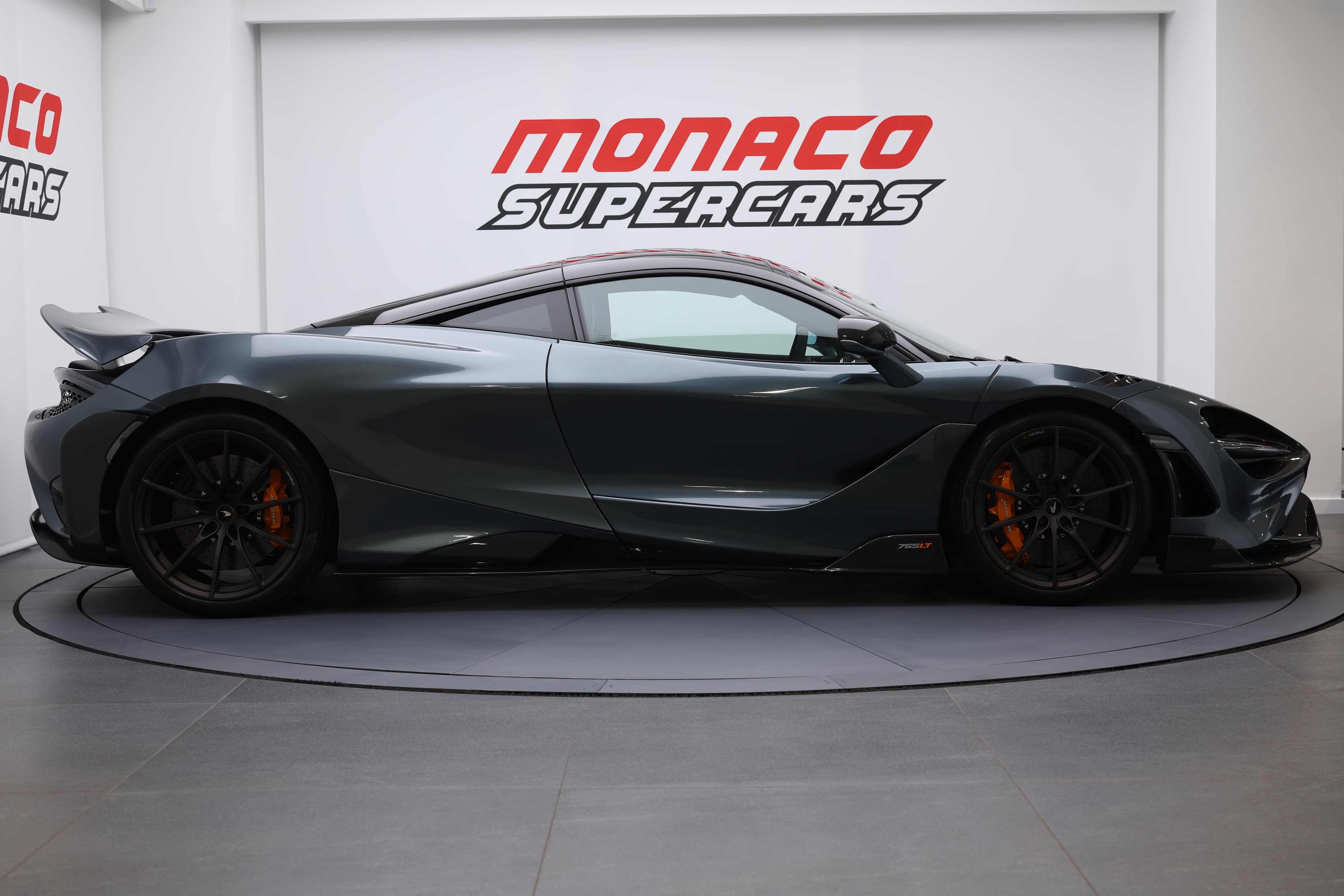 L'image capture le profil d'une McLaren 765LT, mettant en évidence ses lignes aérodynamiques, sa silhouette basse et ses détails agressifs, soulignant son design emblématique et sa performance exceptionnelle.