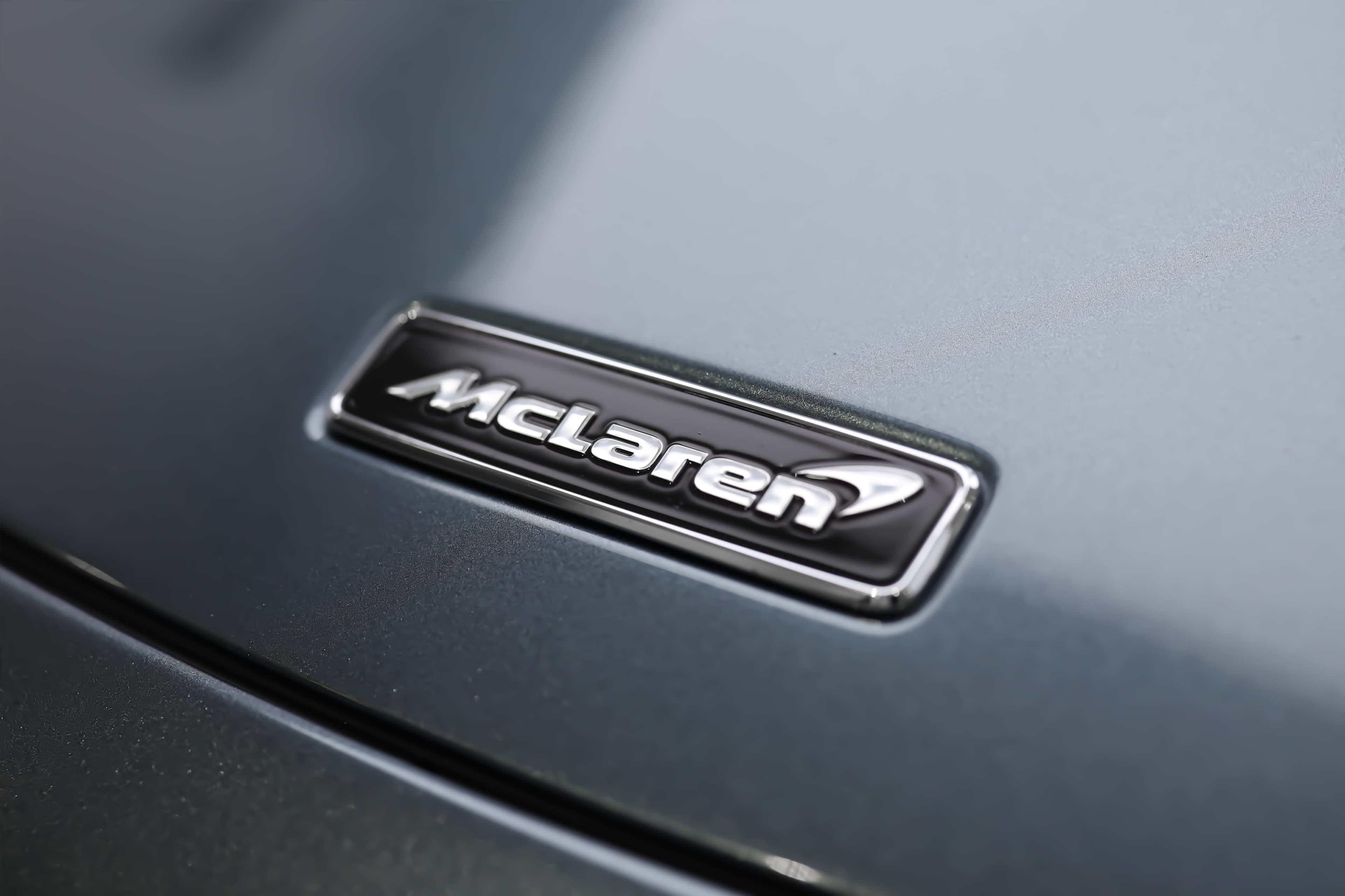 L'image se concentre sur le logo de McLaren sur le capot de la 765LT, mettant en valeur son design emblématique et élégant, qui symbolise la performance et l'innovation de la marque.