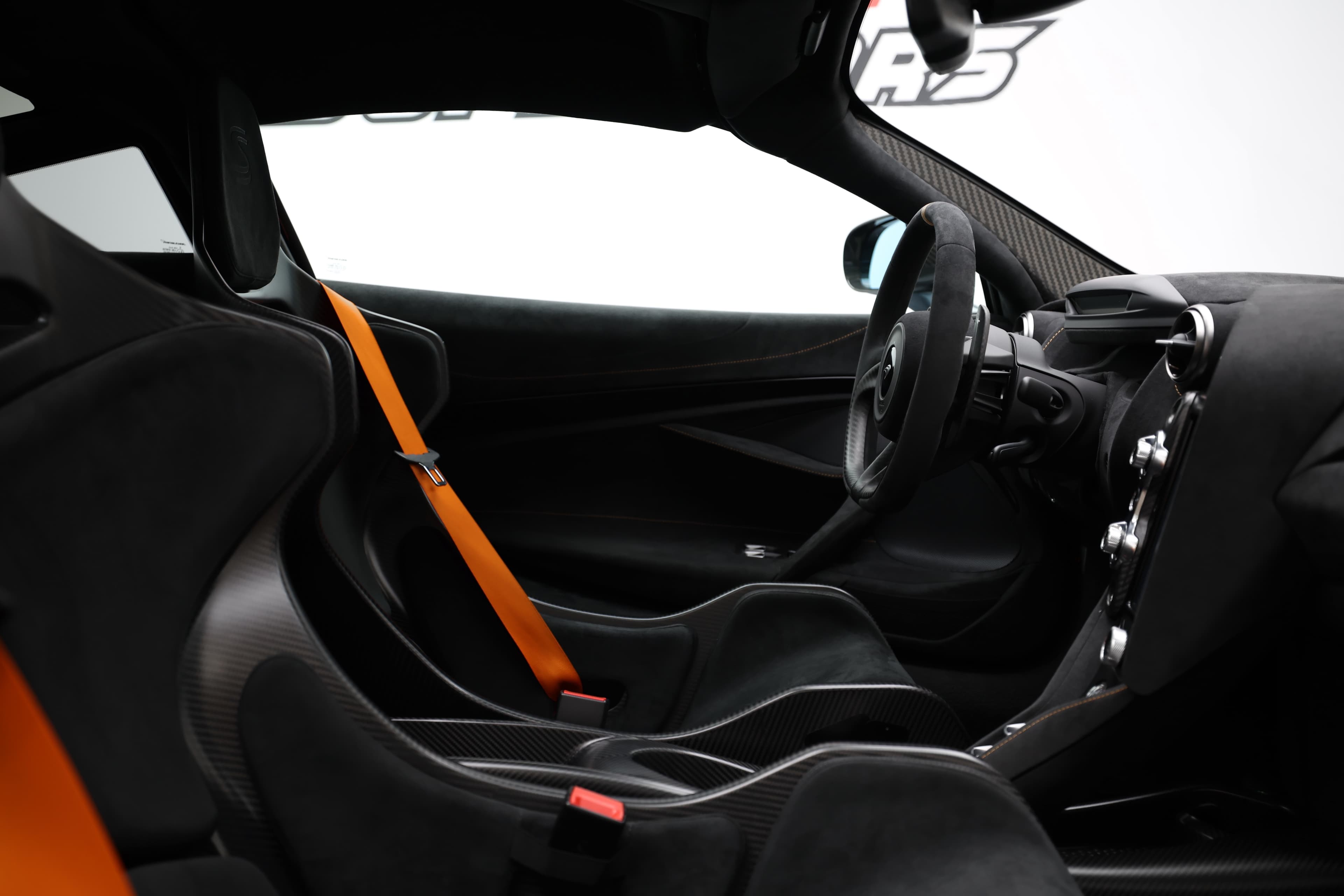 L'image montre l'intérieur du siège de la McLaren P1, en mettant en avant la ceinture de sécurité orange, qui ajoute une touche dynamique et sportive à l'habitacle, tout en soulignant l'importance de la sécurité et du design.