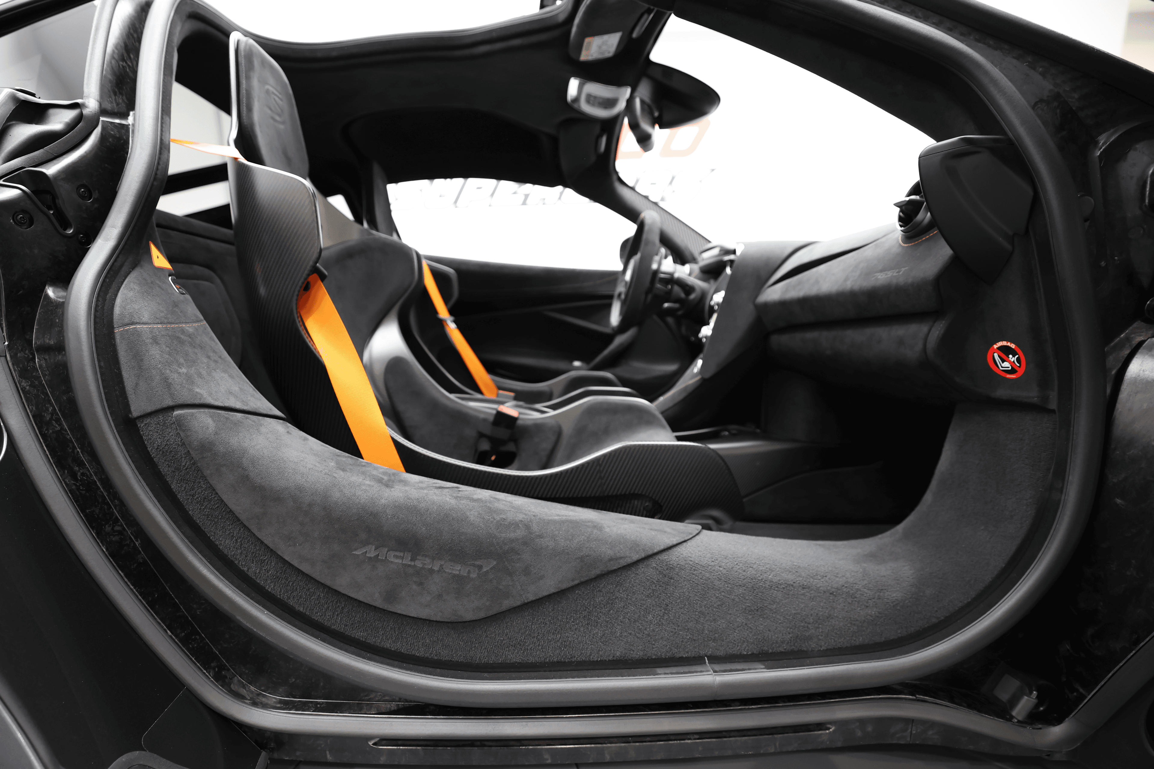 L'image met en avant l'intérieur côté passager de la McLaren P1, mettant en lumière le siège, qui allie confort et sportivité, ainsi que les matériaux luxueux et les finitions haut de gamme qui caractérisent cette supercar emblématique.