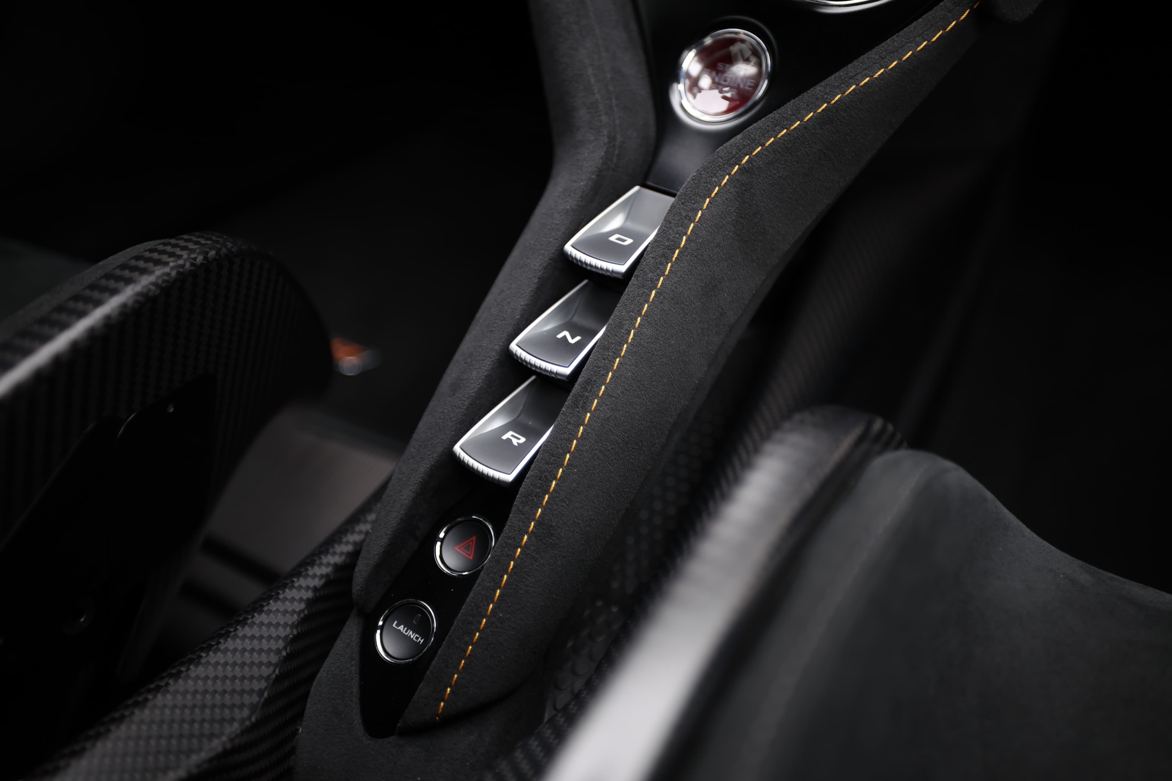 L'image montre un bouton de la console centrale d'une McLaren, mettant en avant son design élégant et fonctionnel. Les détails raffinés et les matériaux haut de gamme témoignent de l'expertise de la marque dans l'ingénierie automobile et le luxe.