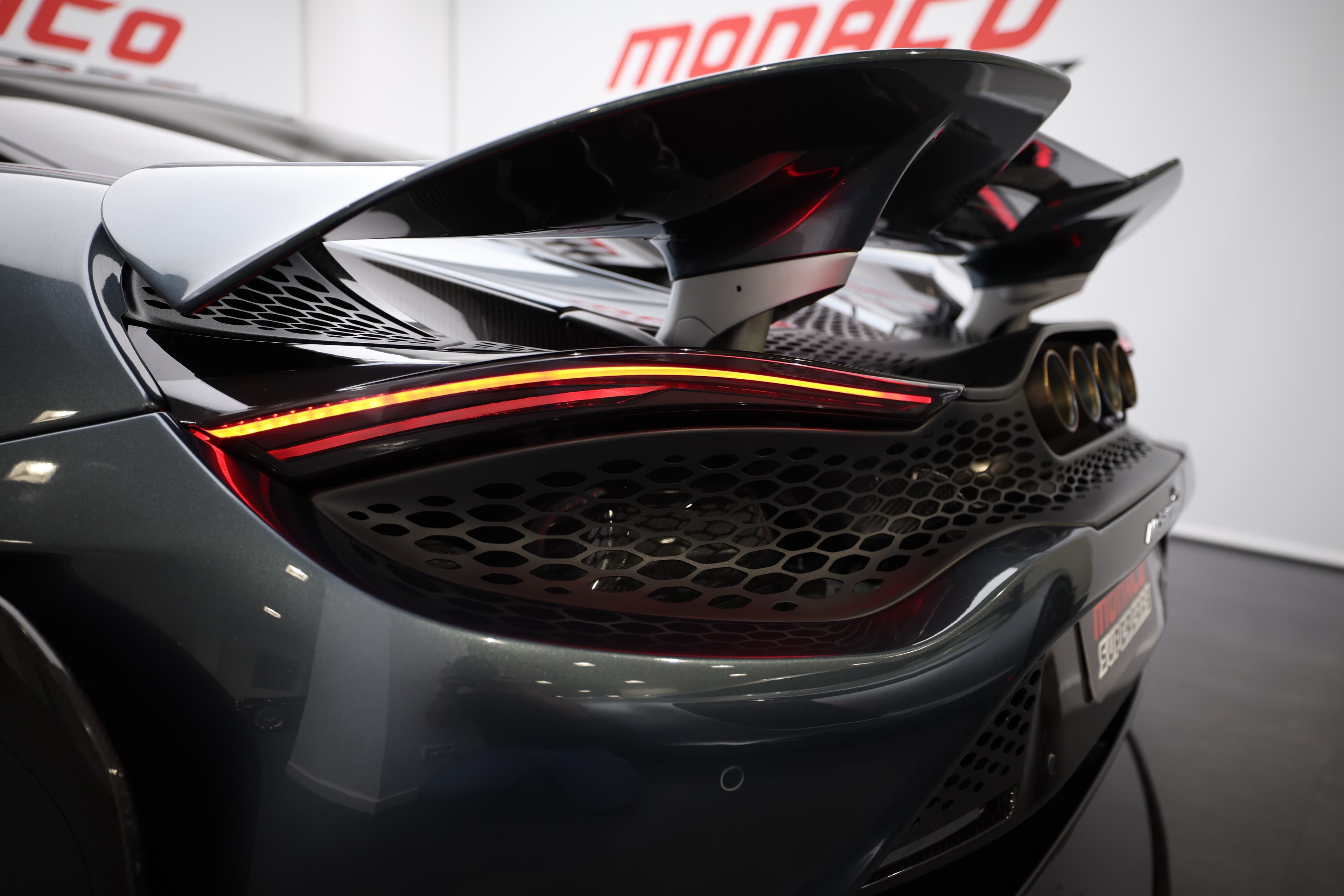 L'image montre un feu arrière allumé d'un véhicule, mettant en avant son design distinctif et moderne. Les lumières illuminées créent une ambiance dynamique, tout en assurant la visibilité et la sécurité sur la route. Les détails du feu arrière illustrent également l'ingénierie et le style de la marque.