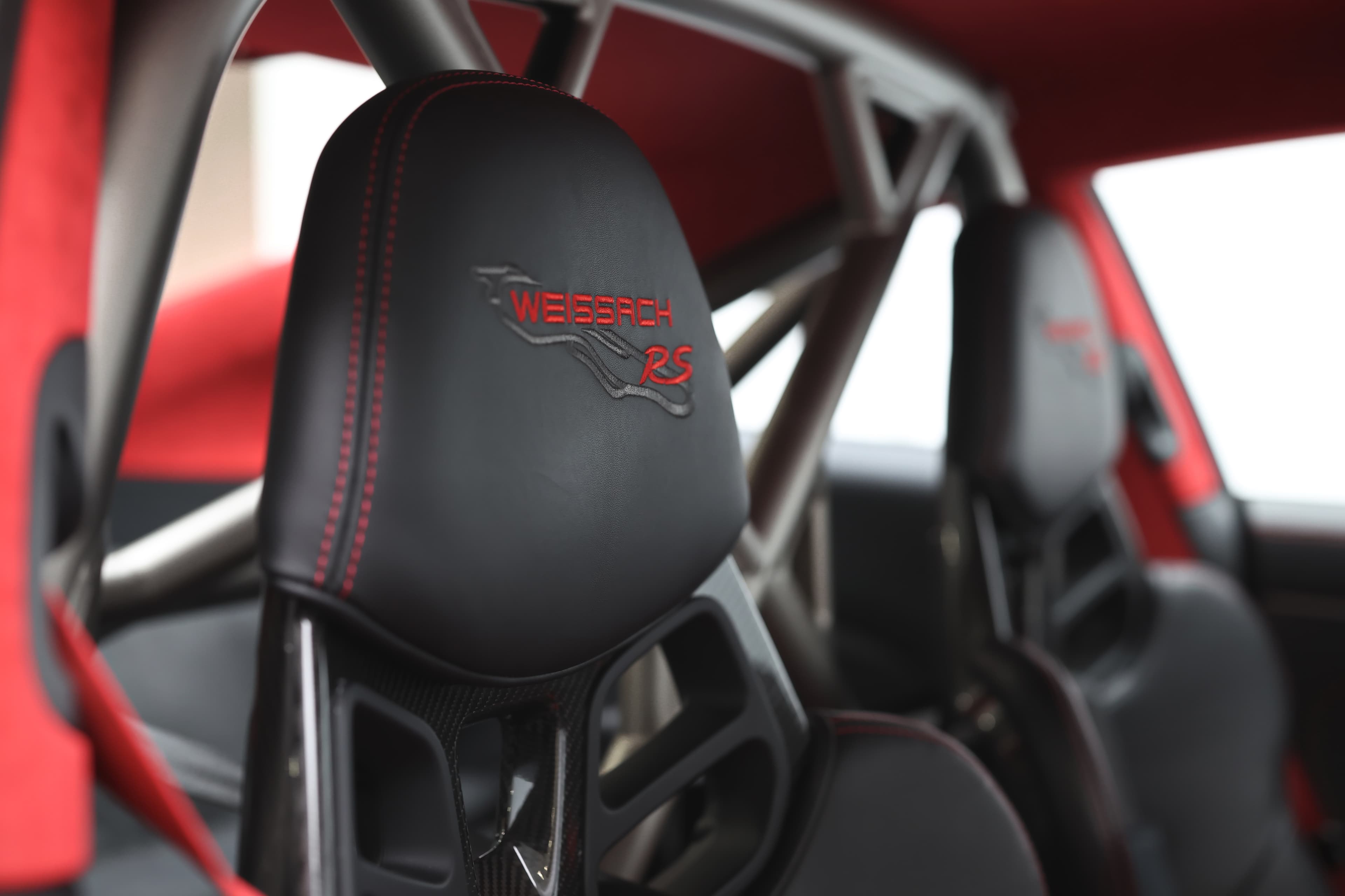 Photo de l'appuie-tête avec surpiqûre rouge et arceau en titane de la Porsche 911 GT2 RS, combinant confort et sécurité tout en ajoutant une touche de sophistication à l'intérieur.