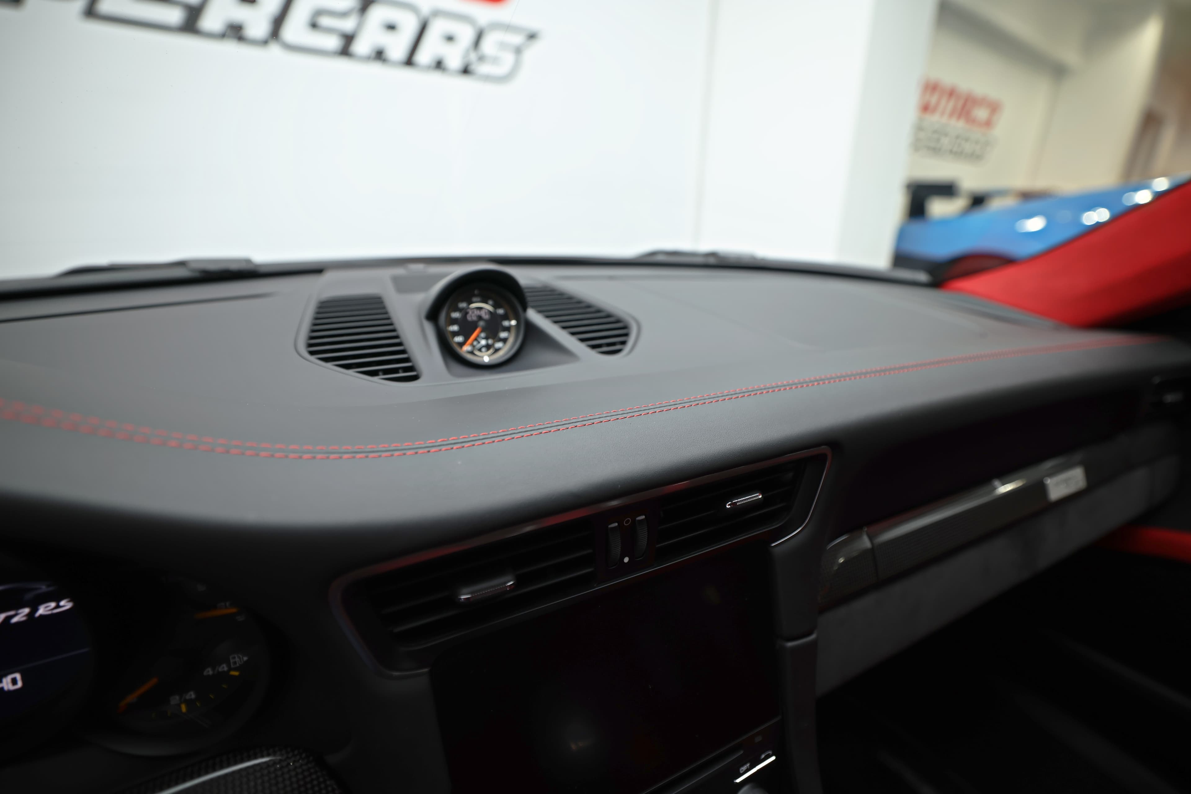 Le tableau de bord en cuir avec surpiqûres rouges de la Porsche 911 GT2 RS incarne le luxe et la sportivité, offrant un design intérieur qui met en avant la performance et une finition haut de gamme.