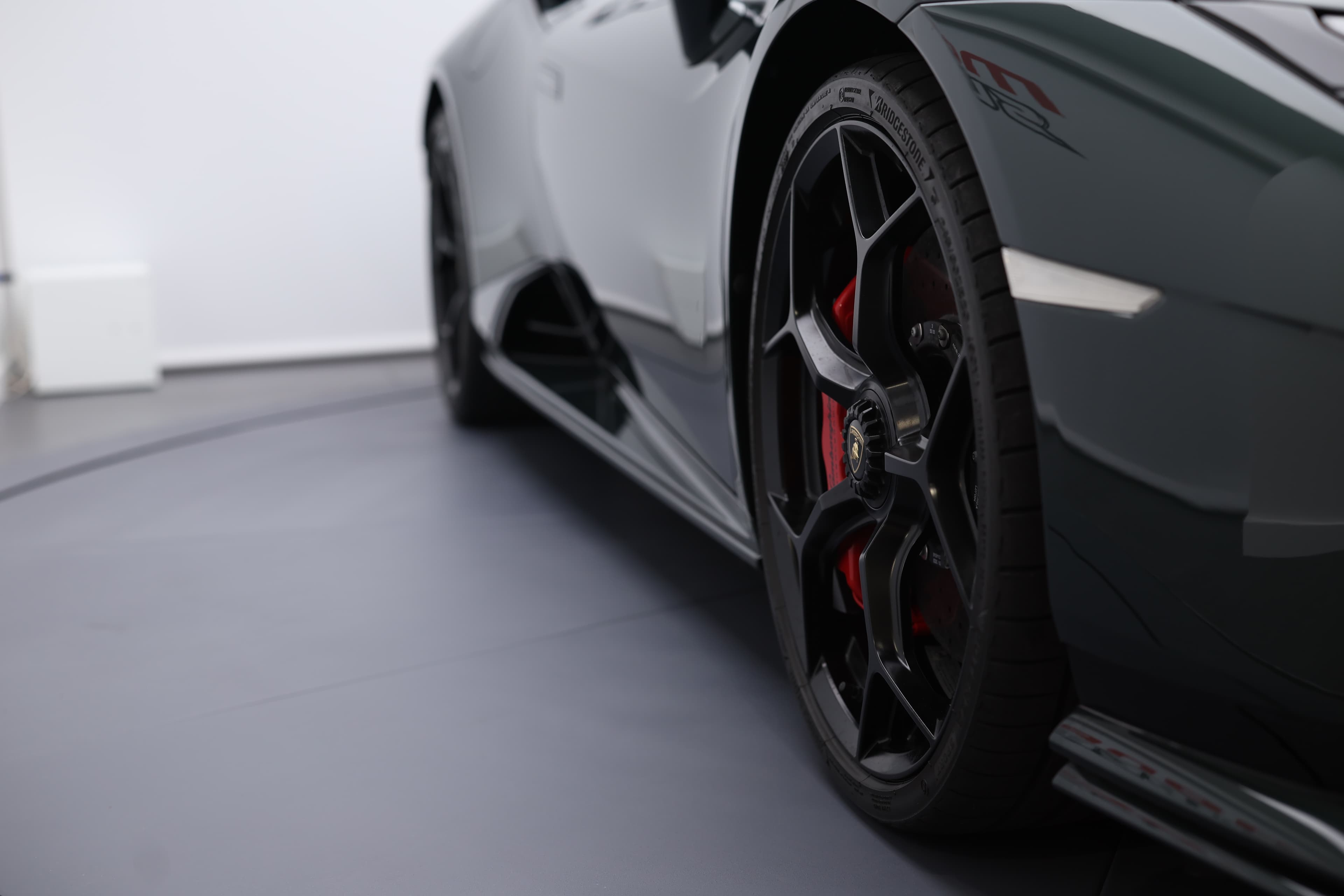 La silhouette profilée de la Lamborghini Huracán Tecnica, capturée de manière à mettre en valeur sa roue avant et son flanc dynamique, révèle une harmonie parfaite entre design aérodynamique et puissance brute, incarnant l'essence même de la performance automobile.