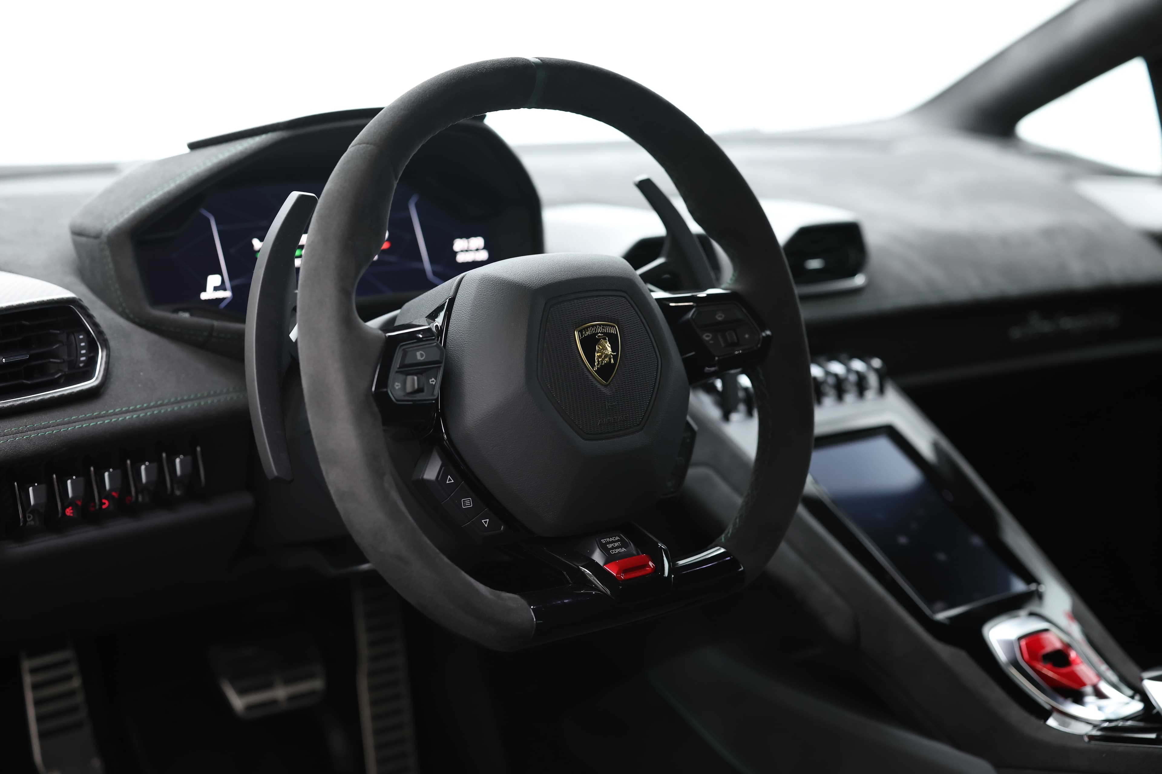 Le volant de la Lamborghini Huracán Tecnica, en Alcantara et carbone, offre une prise en main optimale avec des palettes de changement de vitesse en carbone, alliant sportivité et élégance pour une expérience de conduite immersive.