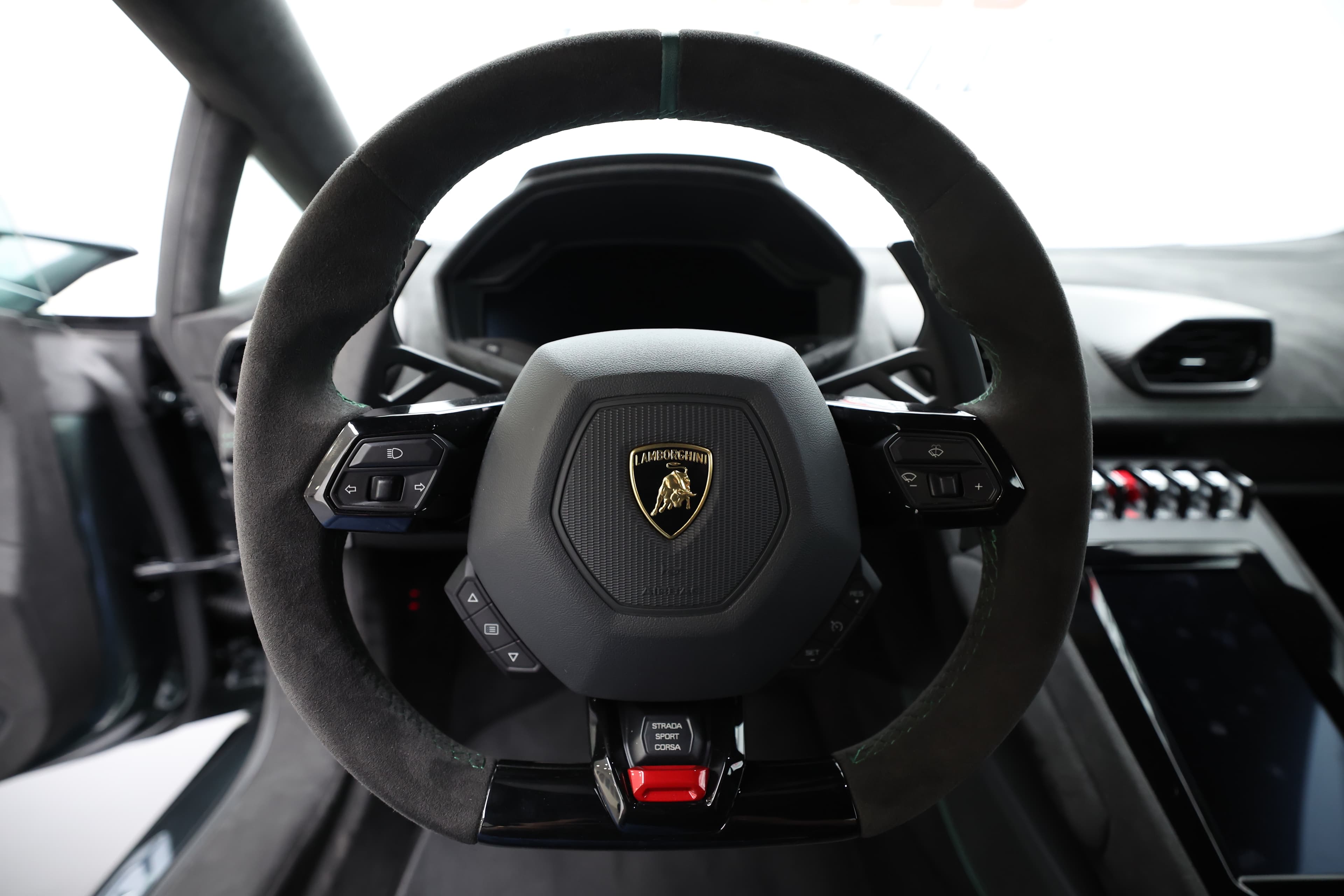 Le volant de la Lamborghini Huracán Tecnica, vu de face, se dresse fièrement devant une console arrière élégante qui abrite le tableau de bord numérique, offrant une lecture claire des informations essentielles tout en intégrant des éléments de design sportif et high-tech.