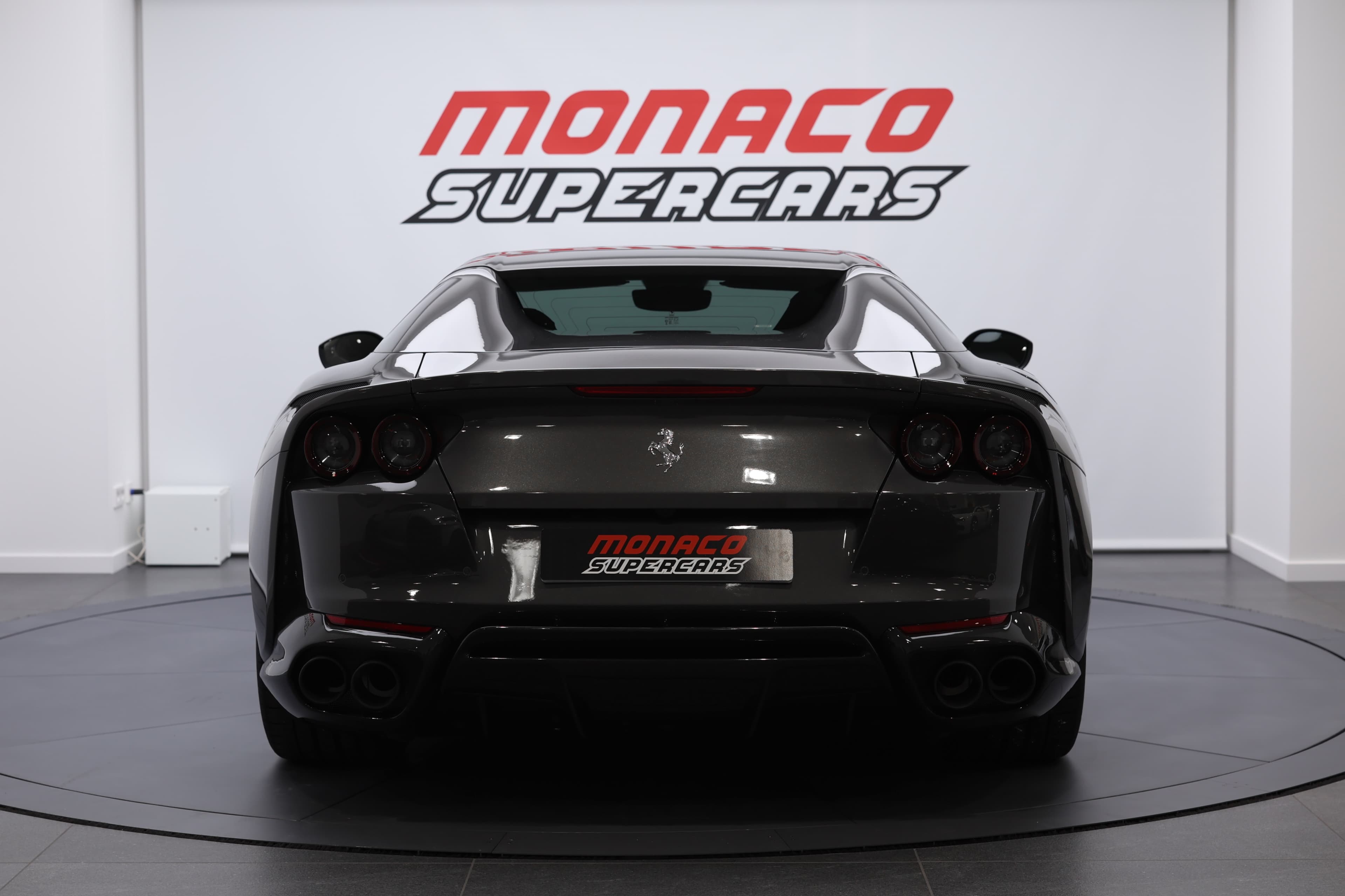 La vue arrière de la Ferrari 812 GTS met en avant son design audacieux, avec des feux arrière emblématiques et un diffuseur agressif, soulignant la puissance du moteur V12 et l'esthétique sportive de ce cabriolet d'exception.