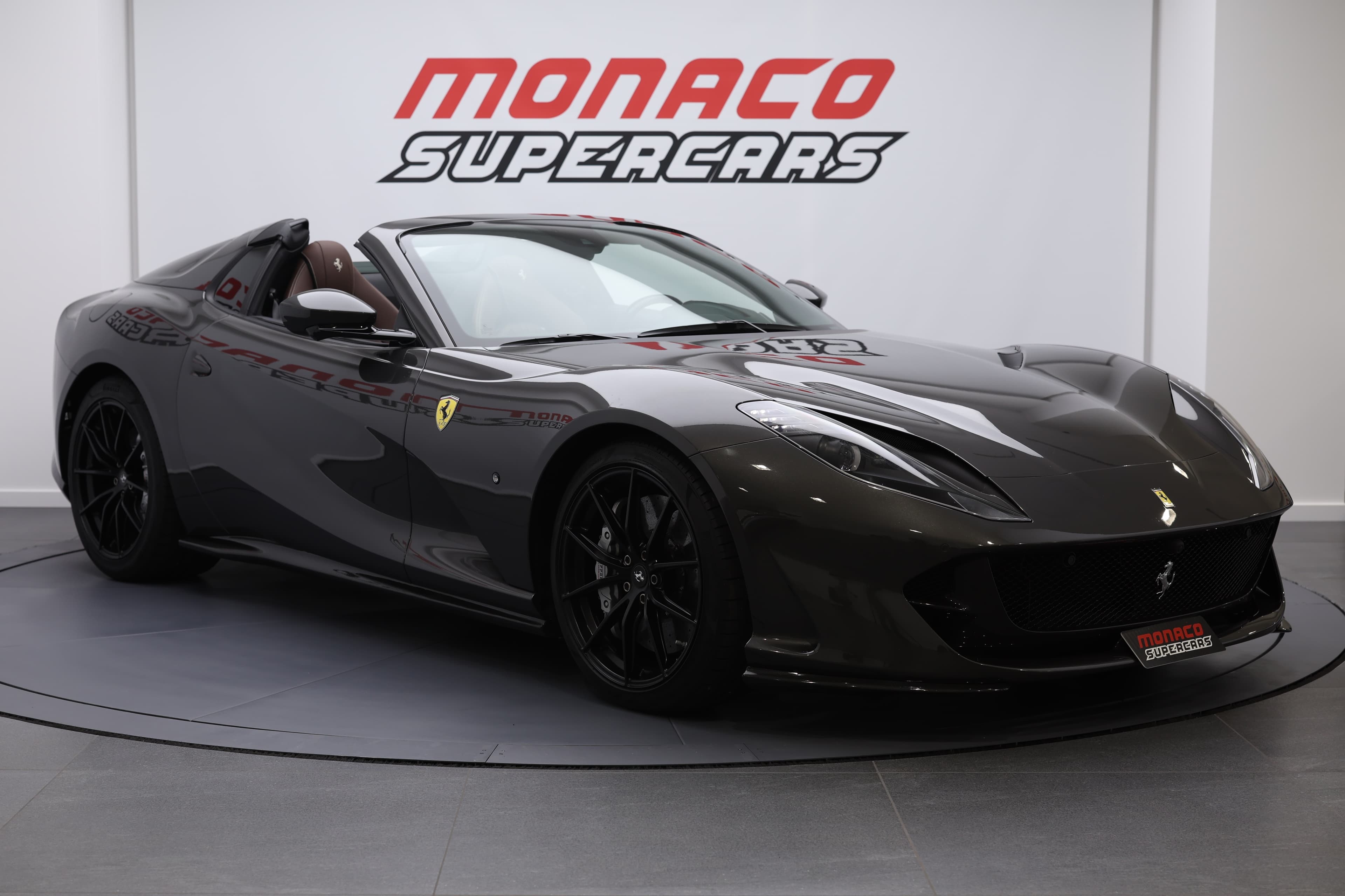 La Ferrari 812 GTS, vue de 3/4 avant avec le toit décapoté, met en avant ses lignes fluides et son allure sportive, incarnant l'élégance et la puissance sur la route.