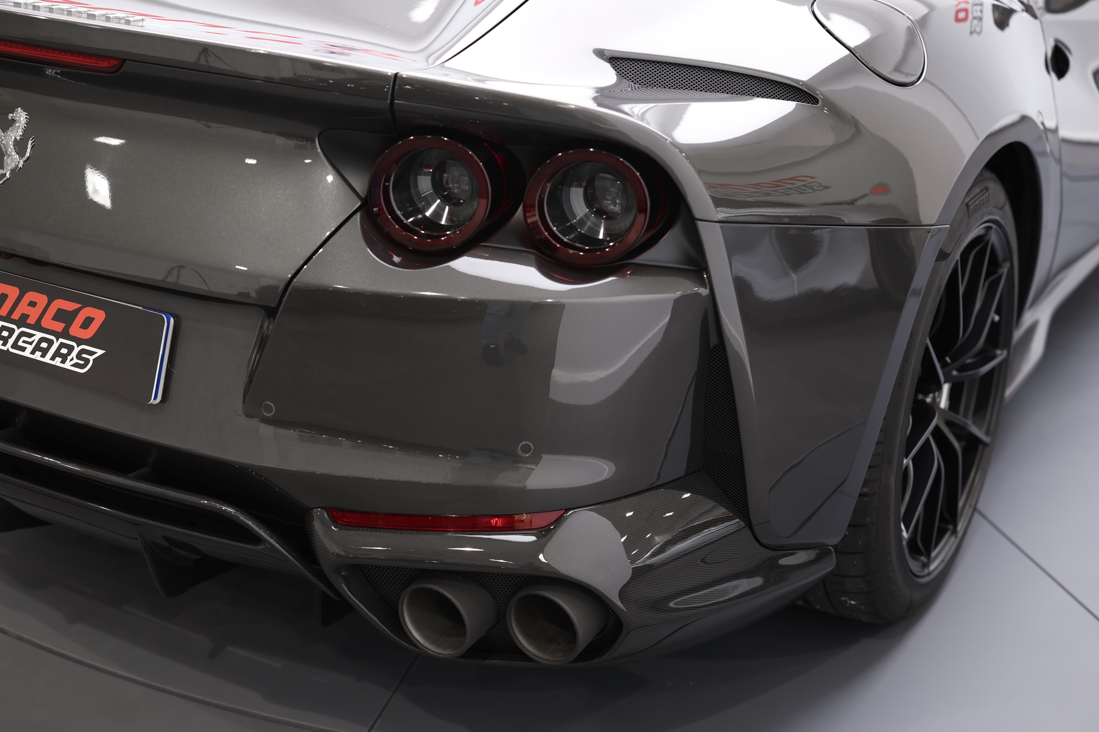 Découvrez le profil arrière captivant de cette Ferrari 812 GTS décapotable en gris canon de fusil, mettant en valeur ses feux arrière emblématiques et son design élégant !