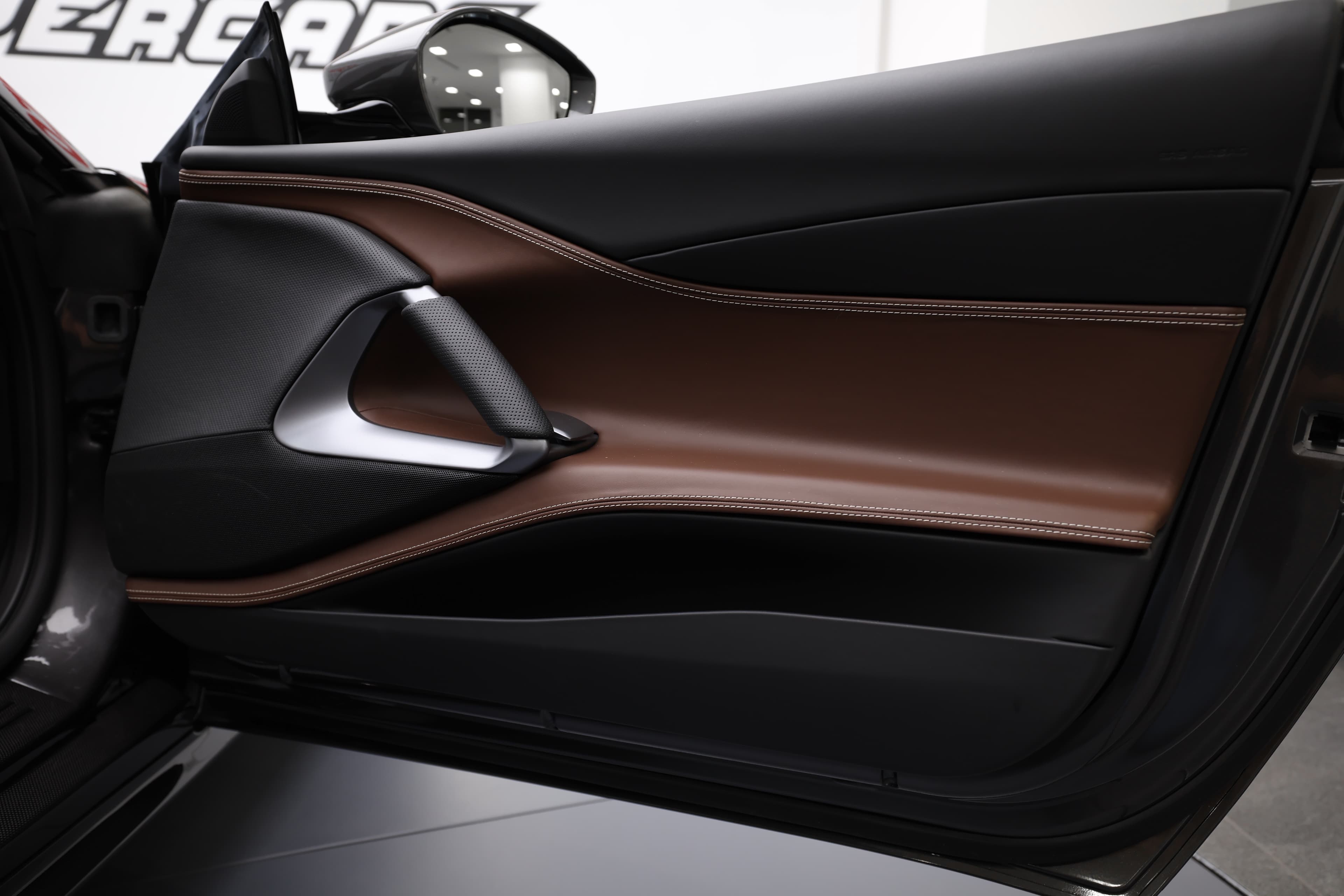 Voici un détail du panneau de porte de la Ferrari 812 GTS, où l'élégance du cuir chocolat se marie parfaitement avec des finitions raffinées. Chaque élément est conçu pour offrir un confort optimal tout en conservant l'identité sportive de cette supercar.
