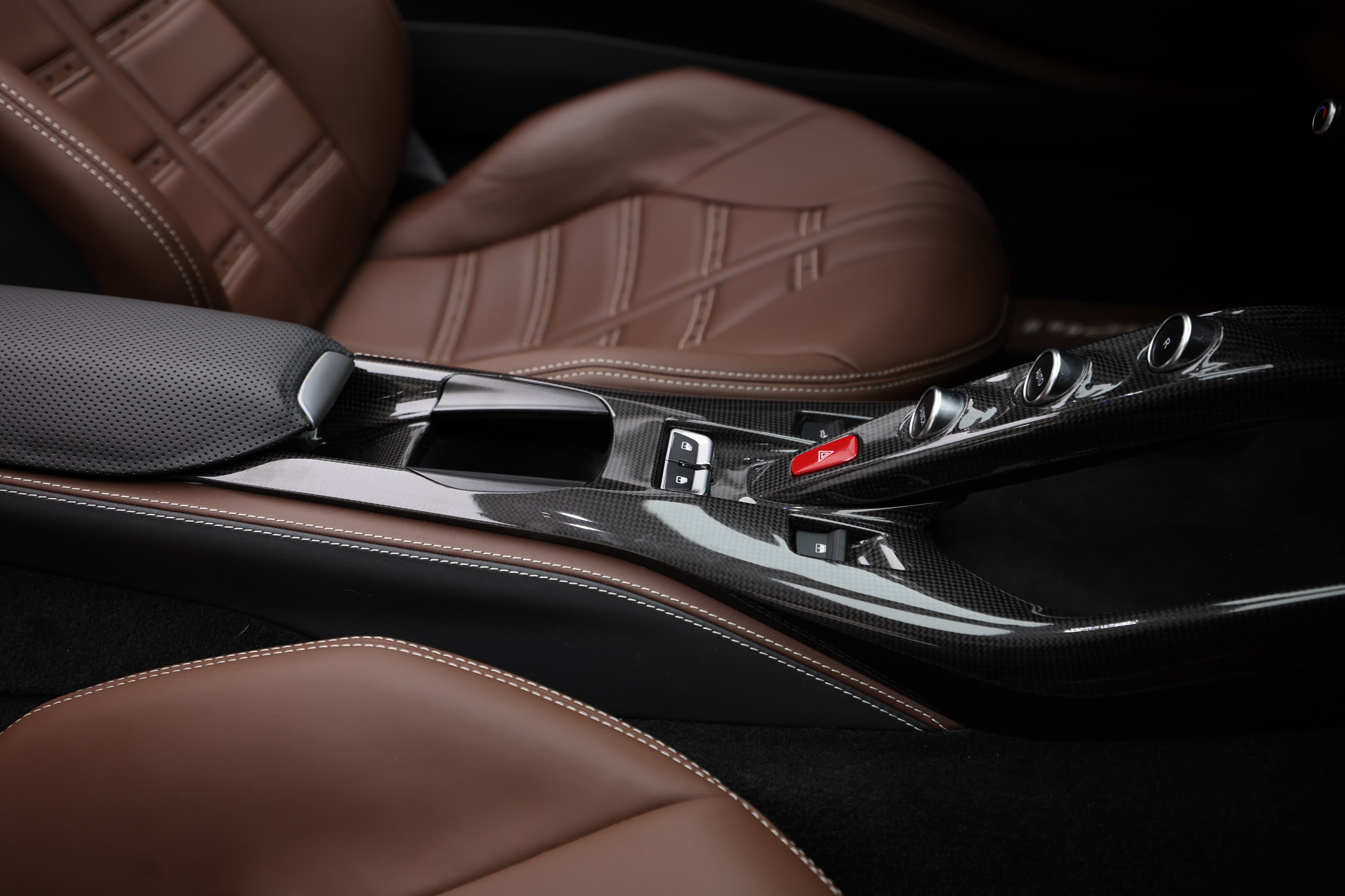 Admirez ce gros plan sur la console centrale de la Ferrari 812 GTS. Les sièges en cuir chocolat sont mis en valeur par des accents en métal, créant un contraste élégant. Chaque détail, du design aux matériaux, reflète la recherche de performance et de luxe de cette supercar.