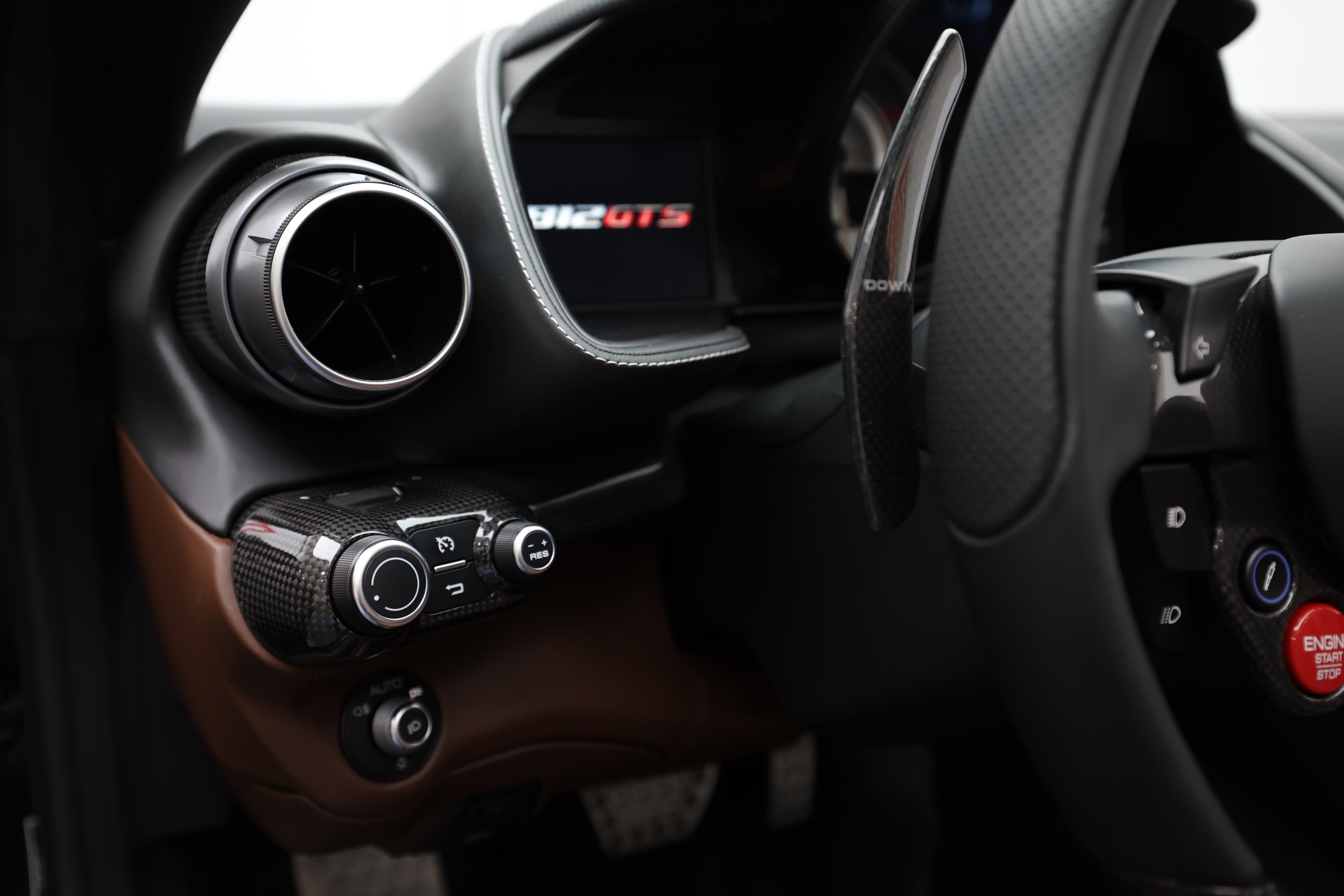 Voici un détail du tableau de bord de la Ferrari 812 GTS, mettant en avant les commandes intuitives et le badge GTS. Les matériaux de qualité et le design fonctionnel soulignent l'engagement de Ferrari envers l'innovation et l'expérience de conduite optimale.