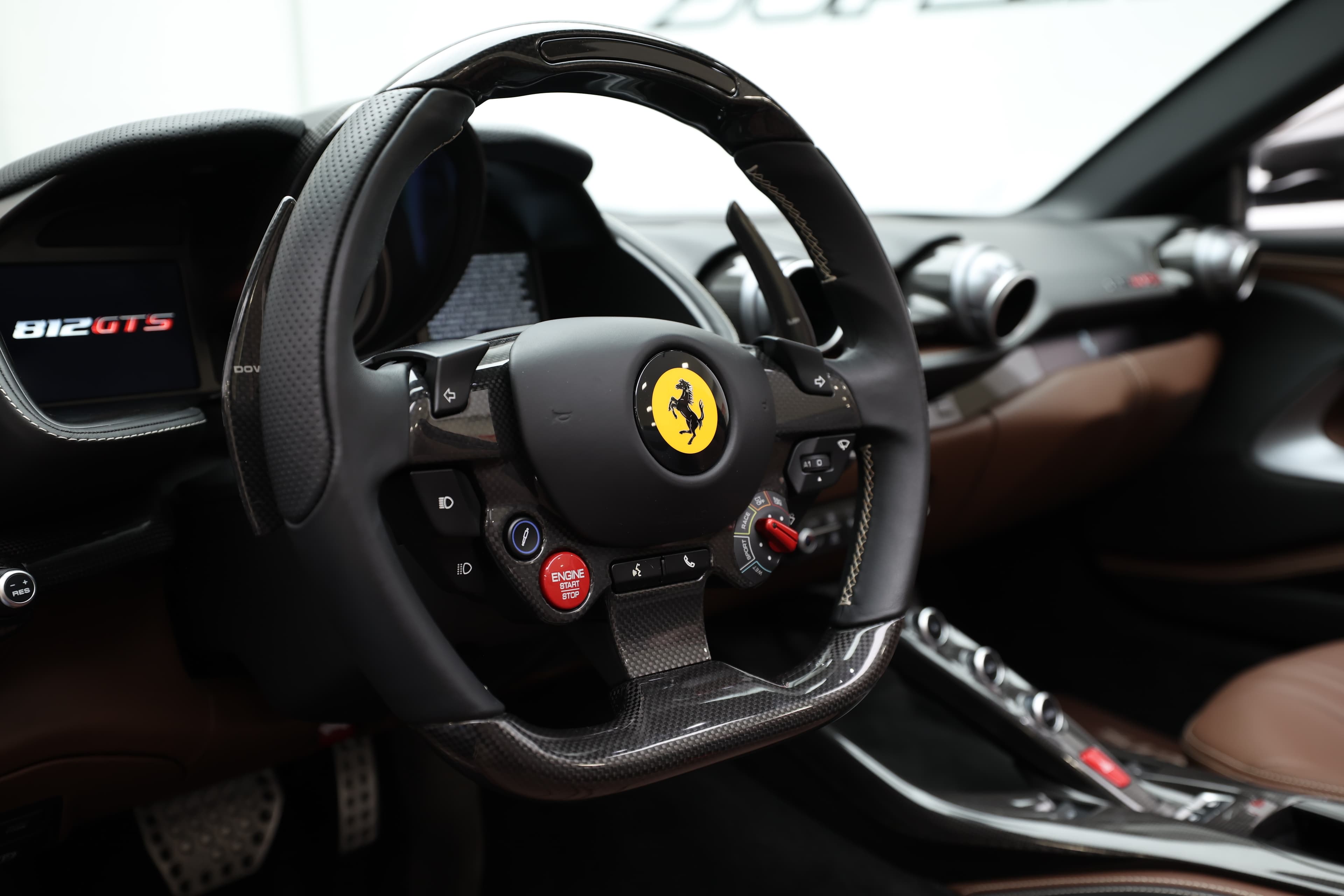 Voici un gros plan du volant de la Ferrari 812 GTS, mettant en avant les commandes sportives et le logo emblématique. Ce volant, à la fois élégant et fonctionnel, est conçu pour offrir une prise en main optimale, renforçant l'expérience de conduite dynamique.