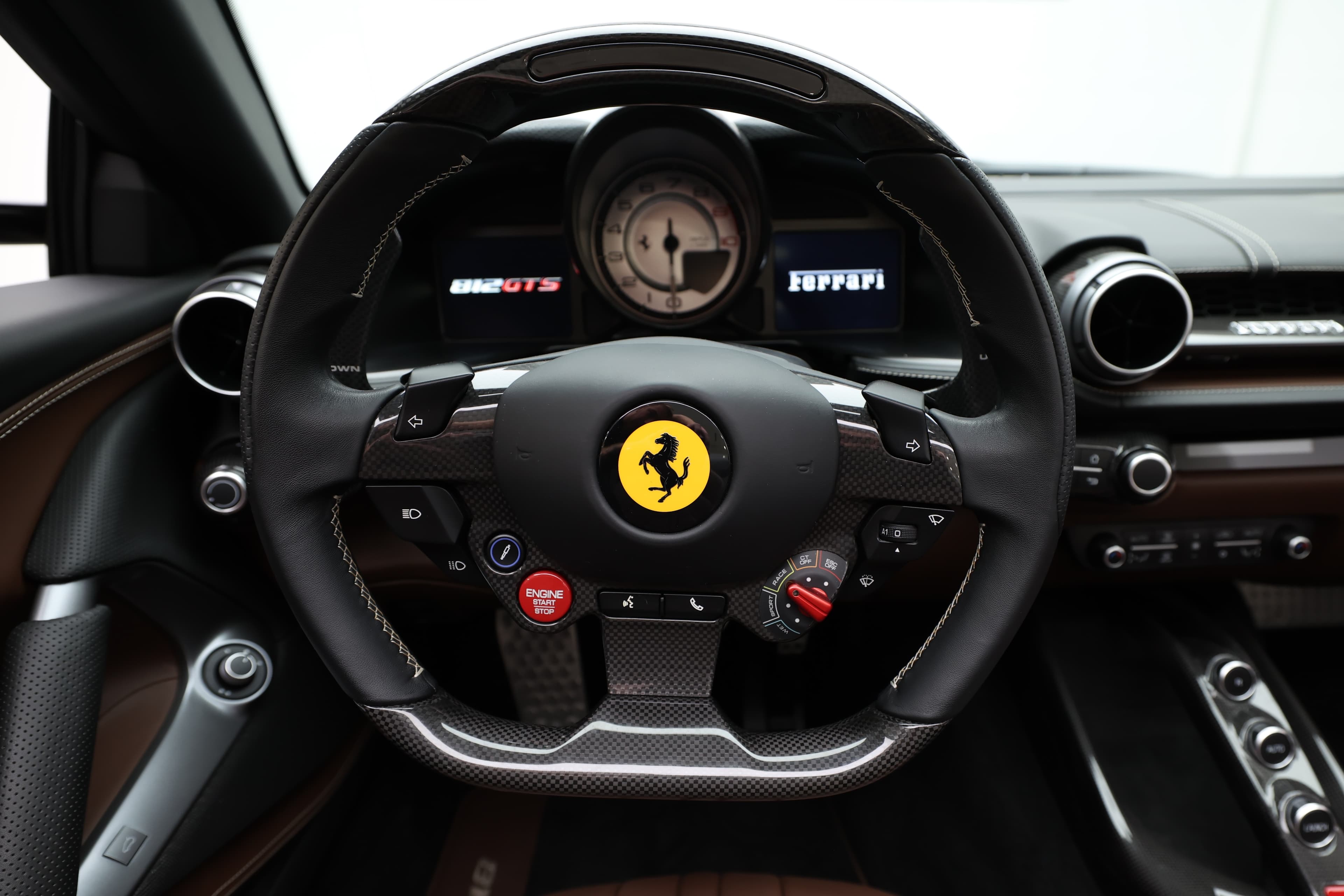 Regardez de près le volant de la Ferrari 812 GTS, avec son logo emblématique au centre. Les instruments numériques à l'arrière offrent une lecture intuitive, tandis que les commandes sportives permettent un accès rapide aux fonctionnalités essentielles, renforçant l'aspect dynamique de la conduite.