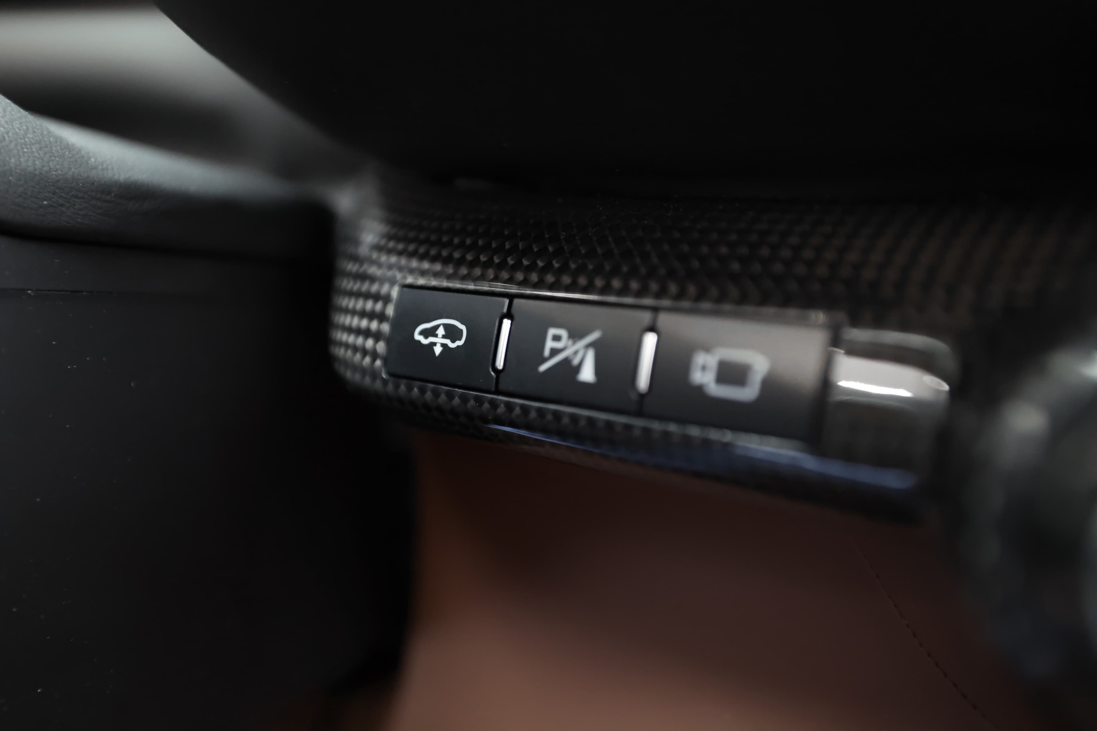 Voici un gros plan des commandes de la Ferrari 812 GTS. Ces boutons spécifiques permettent de contrôler diverses fonctions, offrant ainsi une expérience de conduite intuitive et réactive, tout en restant fidèle au style sportif de la marque.