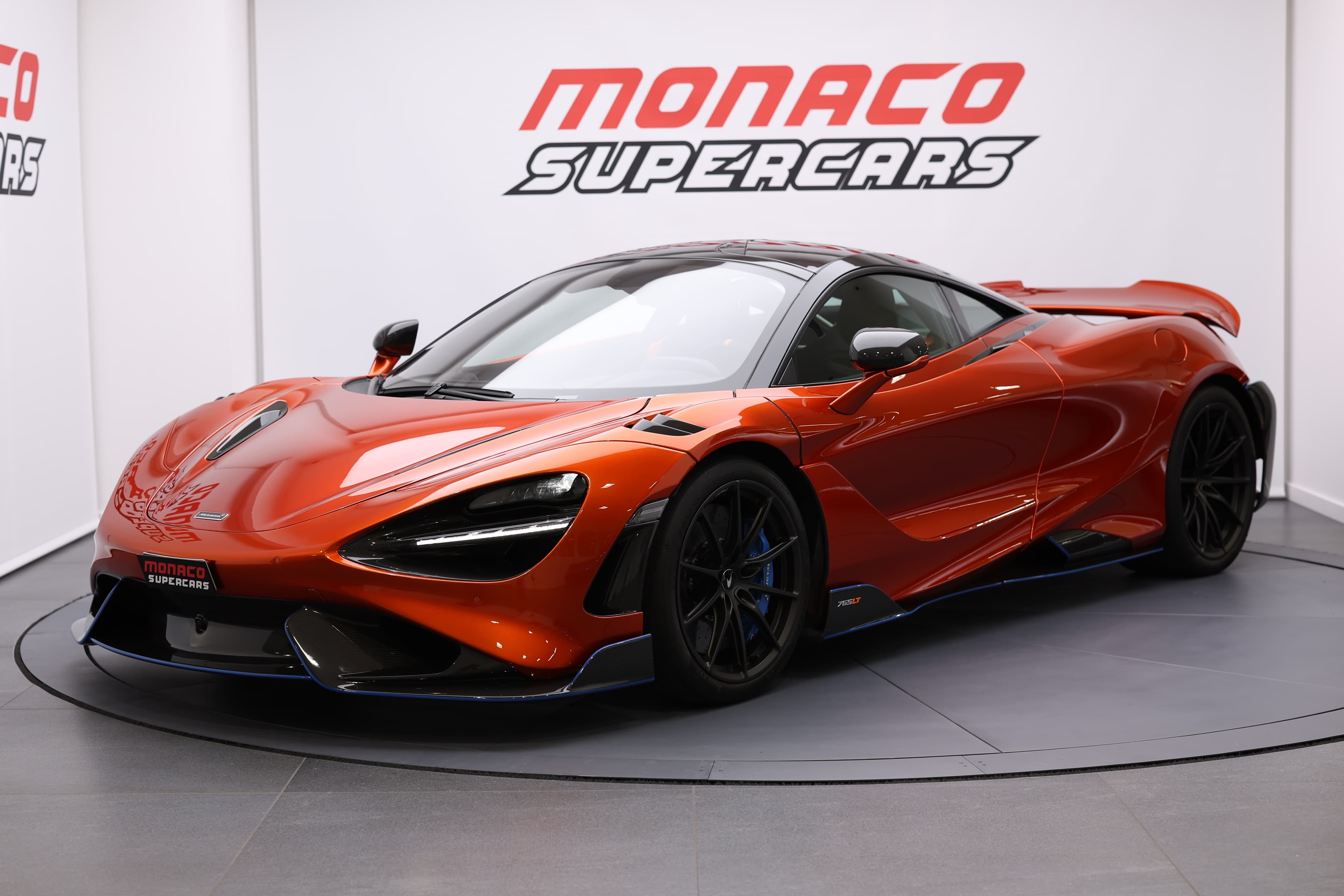 Vue de trois quarts avant de la McLaren 765LT, mettant en avant son design agressif et ses éléments aérodynamiques, soulignant l'allure futuriste et la performance de cette supercar.