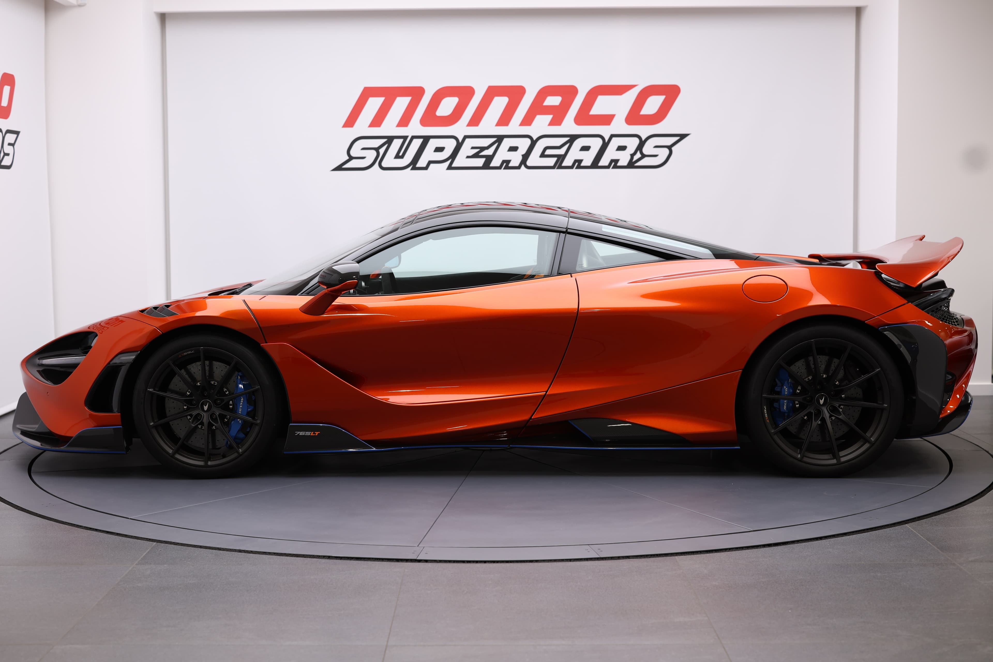 Vue latérale de la McLaren 765LT orange volcano, mettant en avant ses lignes fluides et son profil élégant, illustrant son design dynamique et sportif.