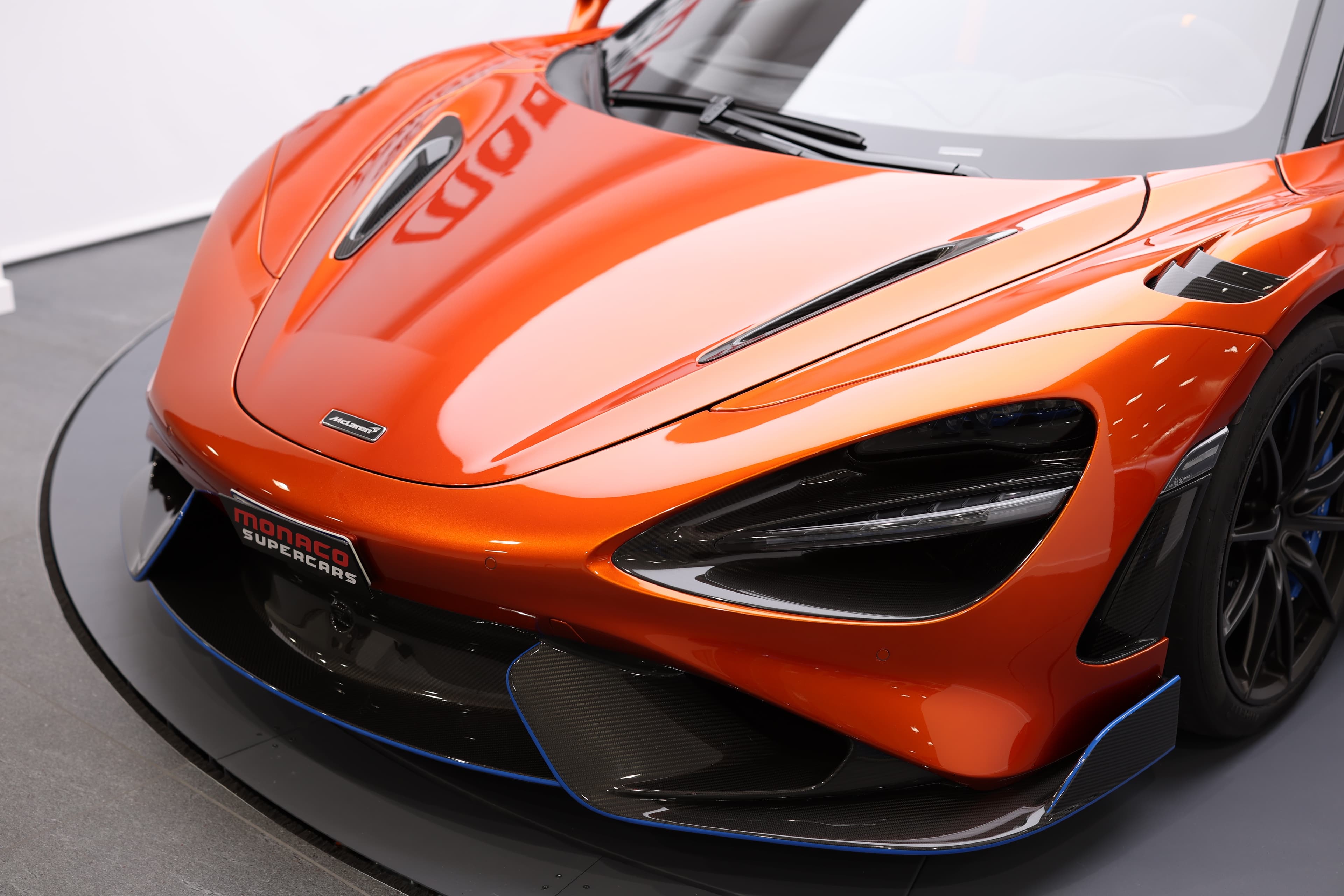 Vue de trois quarts avant de la McLaren 765LT, mettant en avant son design aérodynamique avec des éléments en carbone, soulignant son allure sportive et sa performance exceptionnelle.
