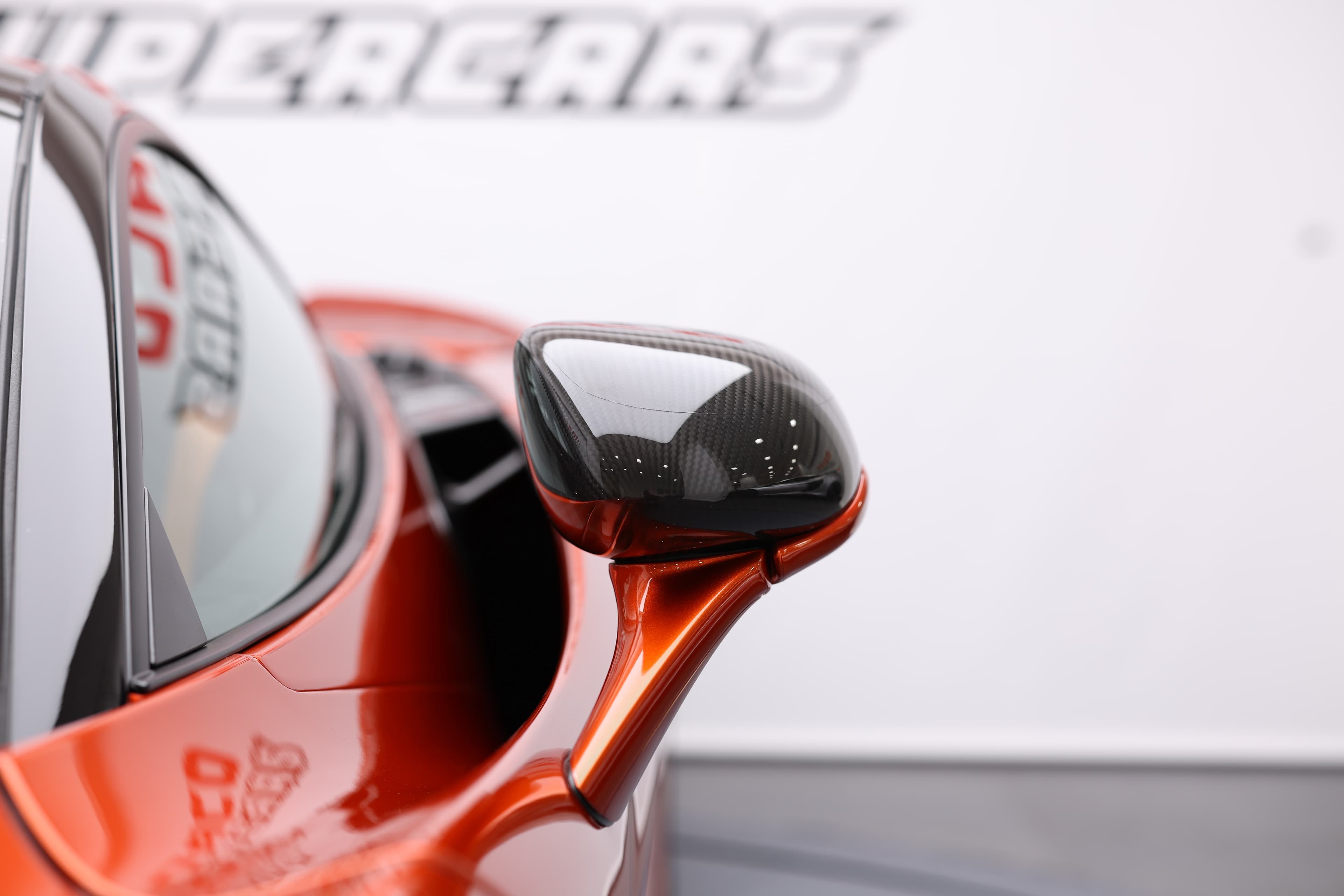 Gros plan sur le rétroviseur de la McLaren 765LT, mettant en avant le matériau en carbone et le design aérodynamique, soulignant l'attention portée aux détails et à la performance.