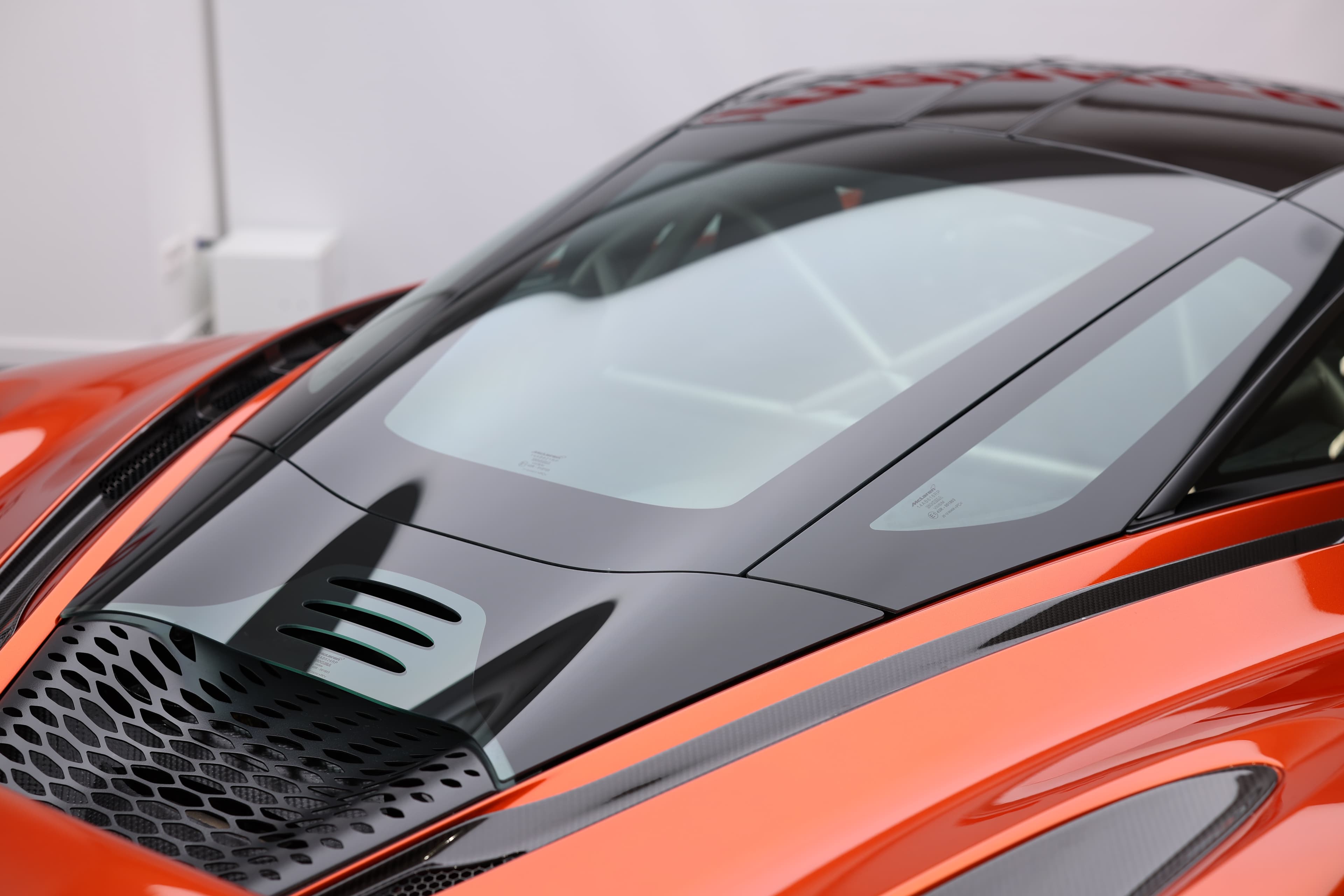 Gros plan sur le toit de la McLaren 765LT, mettant en avant les détails en carbone et les prises d'air, illustrant l'accent mis sur l'aérodynamisme et l'efficacité thermique pour optimiser les performances.