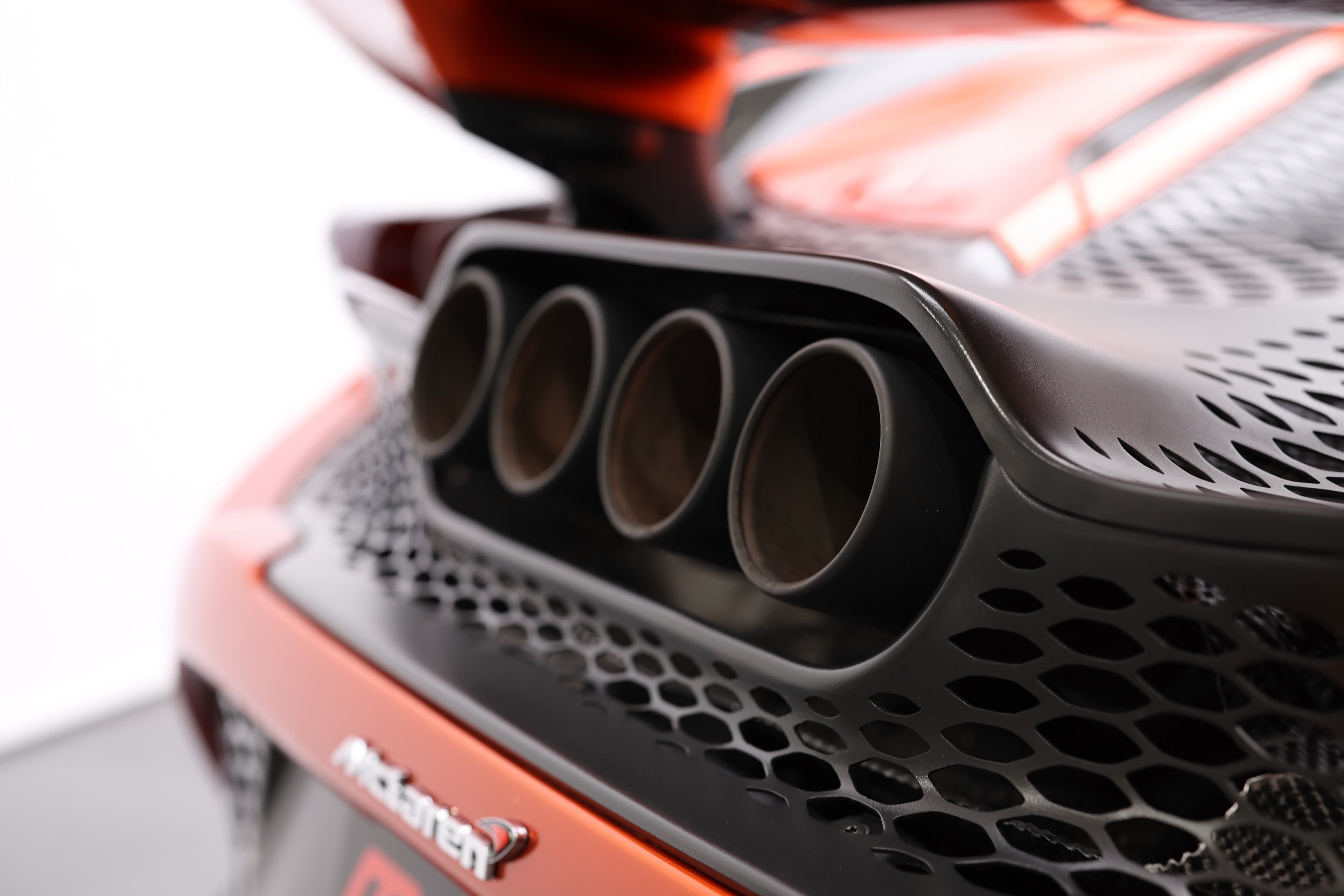 Gros plan sur le système d'échappement de la McLaren 765LT, mettant en avant les sorties d'échappement triples et la conception aérodynamique, soulignant l'importance du son et de la performance dans cette supercar.