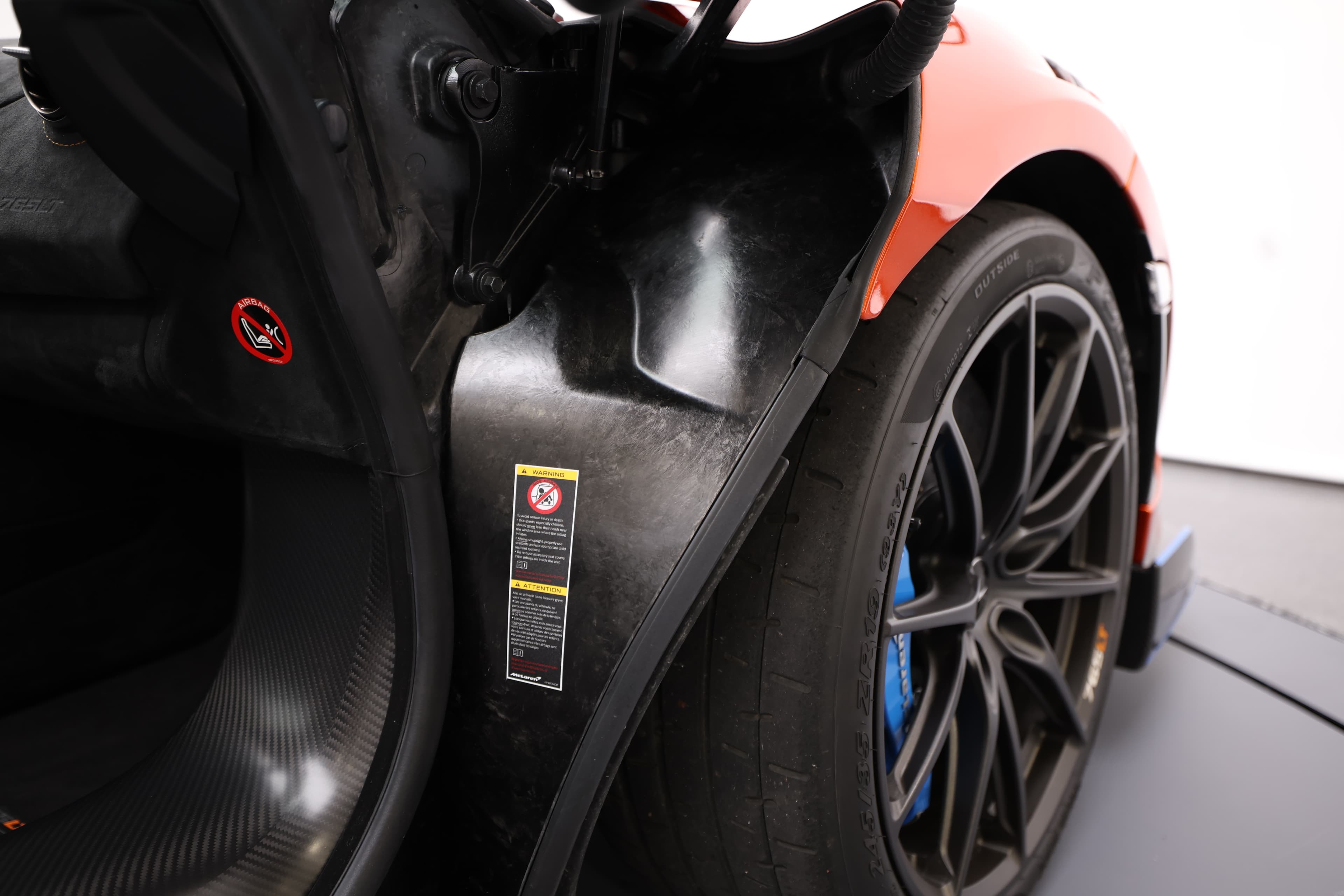 Gros plan sur l'intérieur de la portière de la McLaren 765LT, mettant en avant les matériaux en carbone et les détails de finition, soulignant l'engagement envers la légèreté et la performance.