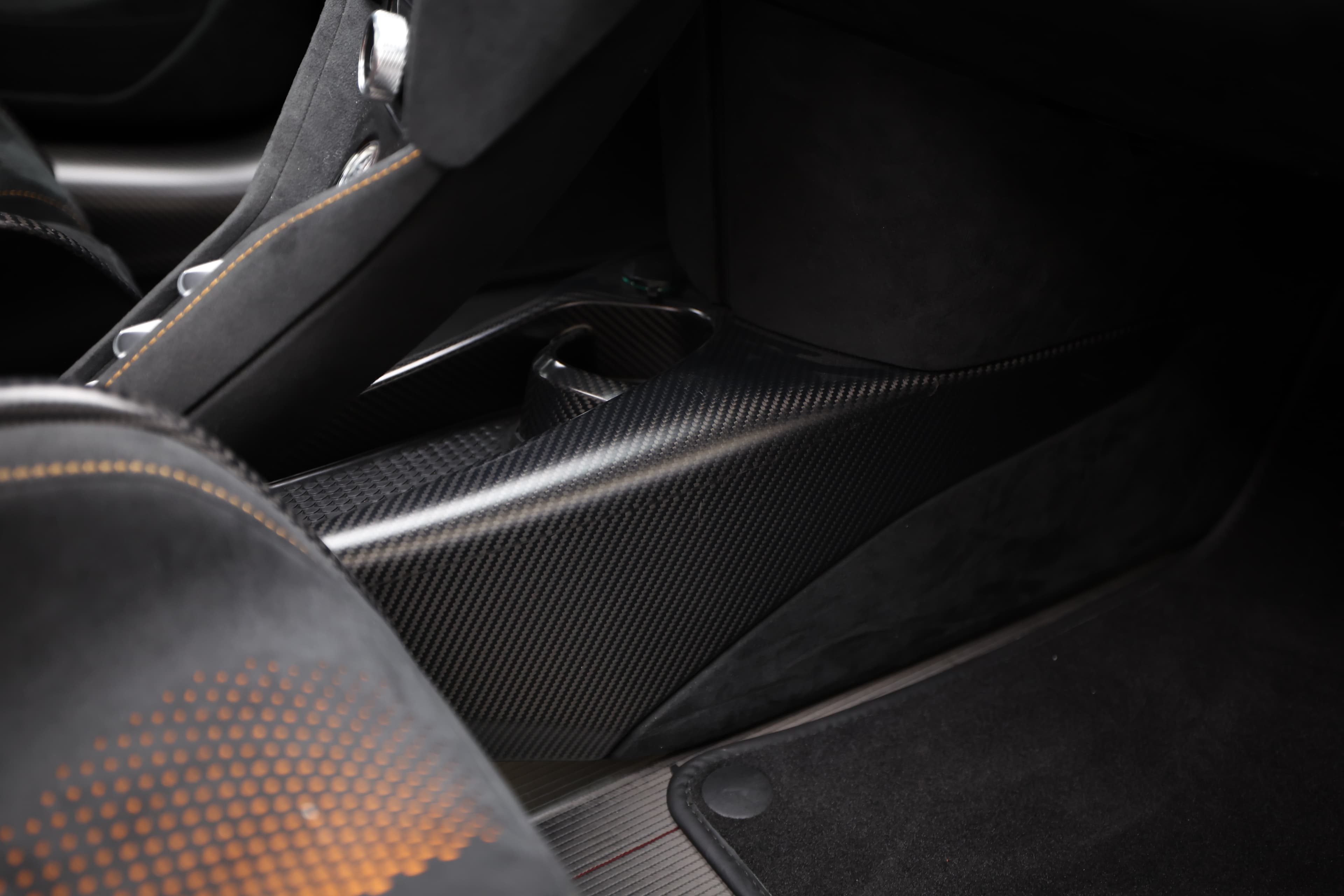 Gros plan sur le détail en carbone de l'intérieur de la McLaren 765LT, mettant en avant la texture et la finition haut de gamme, soulignant le souci du détail et la légèreté des matériaux.