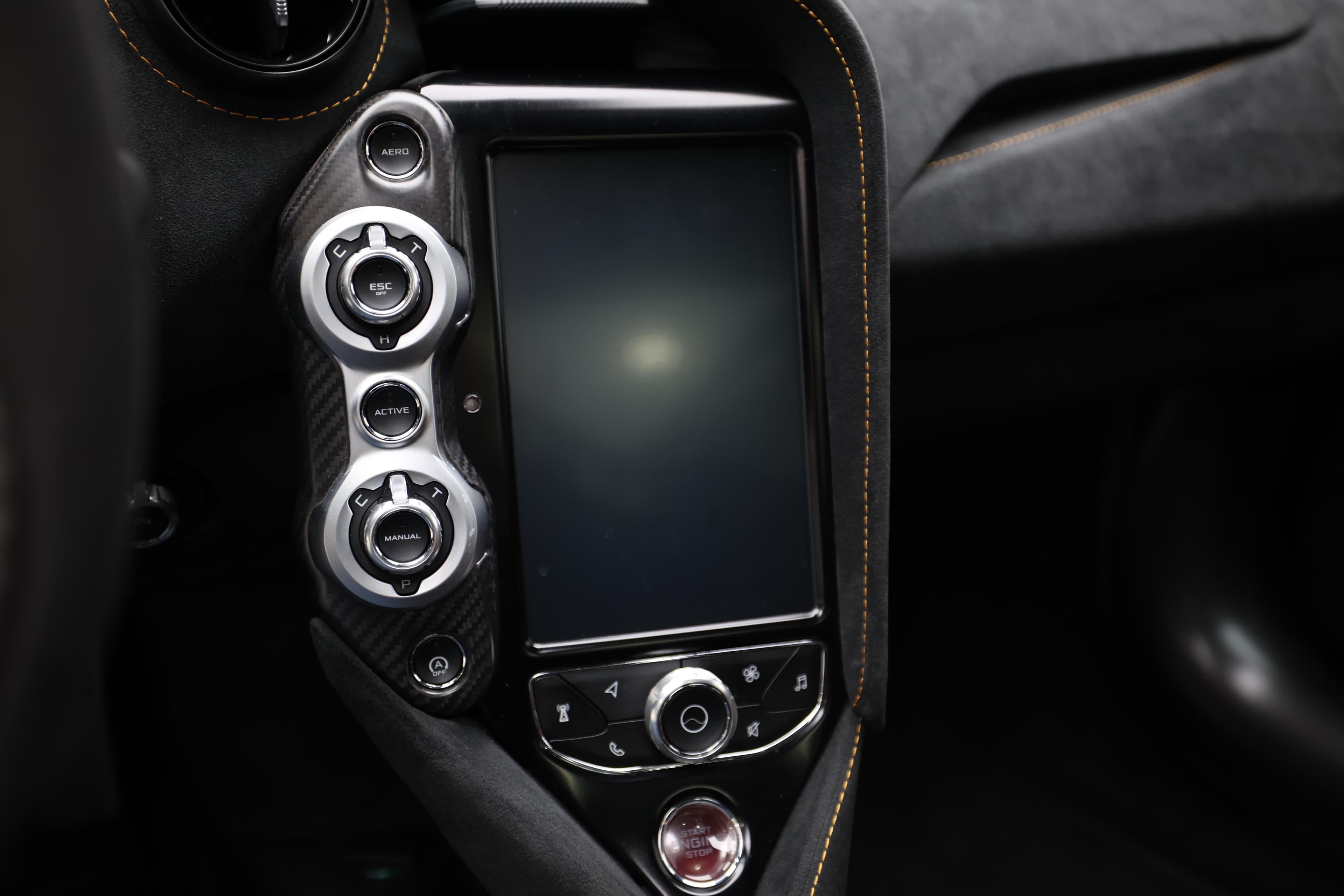 Gros plan sur le panneau de contrôle de la McLaren 765LT, mettant en avant l'écran tactile et les commandes en aluminium, soulignant l'intégration de la technologie et le design raffiné de l'habitacle.