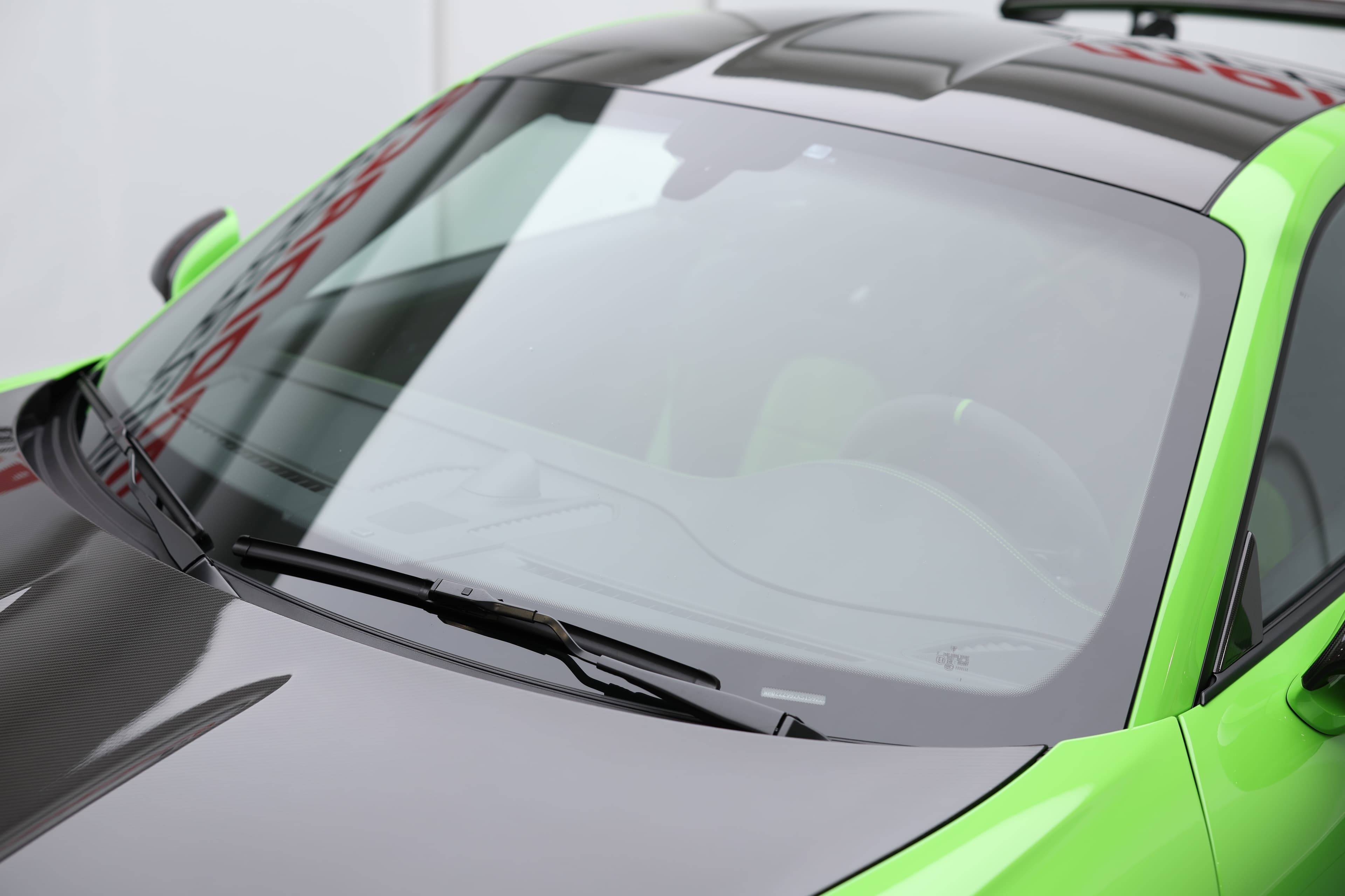 Détail de la Porsche 911 GT3 RS 991 verte mettant en avant le capot en carbone apparent et le pare-brise profilé, soulignant son aérodynamisme et son ADN 100 % performance.